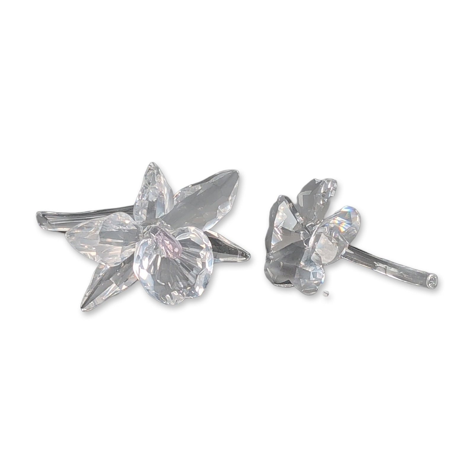Two Swarovski Silver Crystal Figurines, Orchid and Four Leaf Clover: Crystal faceted clear figurines, including a Cattleya orchid and a small four leaf clover. The orchid features five pointed petals and a central ruffled labellum with a faint pink tint, mounted on a b