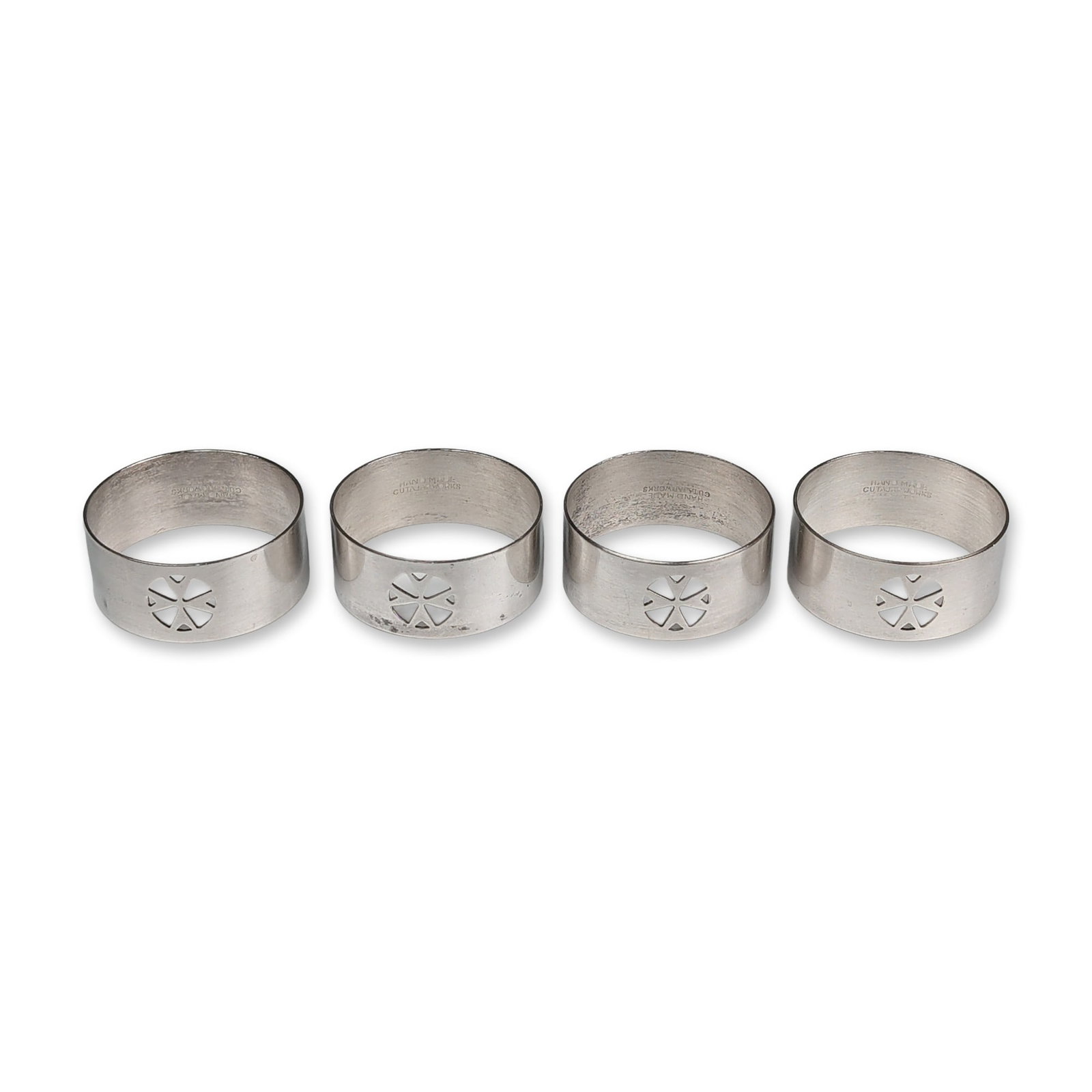 Set of Four Cutajar Works Maltese Silver-Plated Napkin Rings: Maltese silver napkin rings by Cutajar Works, each designed as a wide band featuring a central openwork cutout of an eight-pointed Maltese cross. The pieces exhibit a polished exterior finish and show