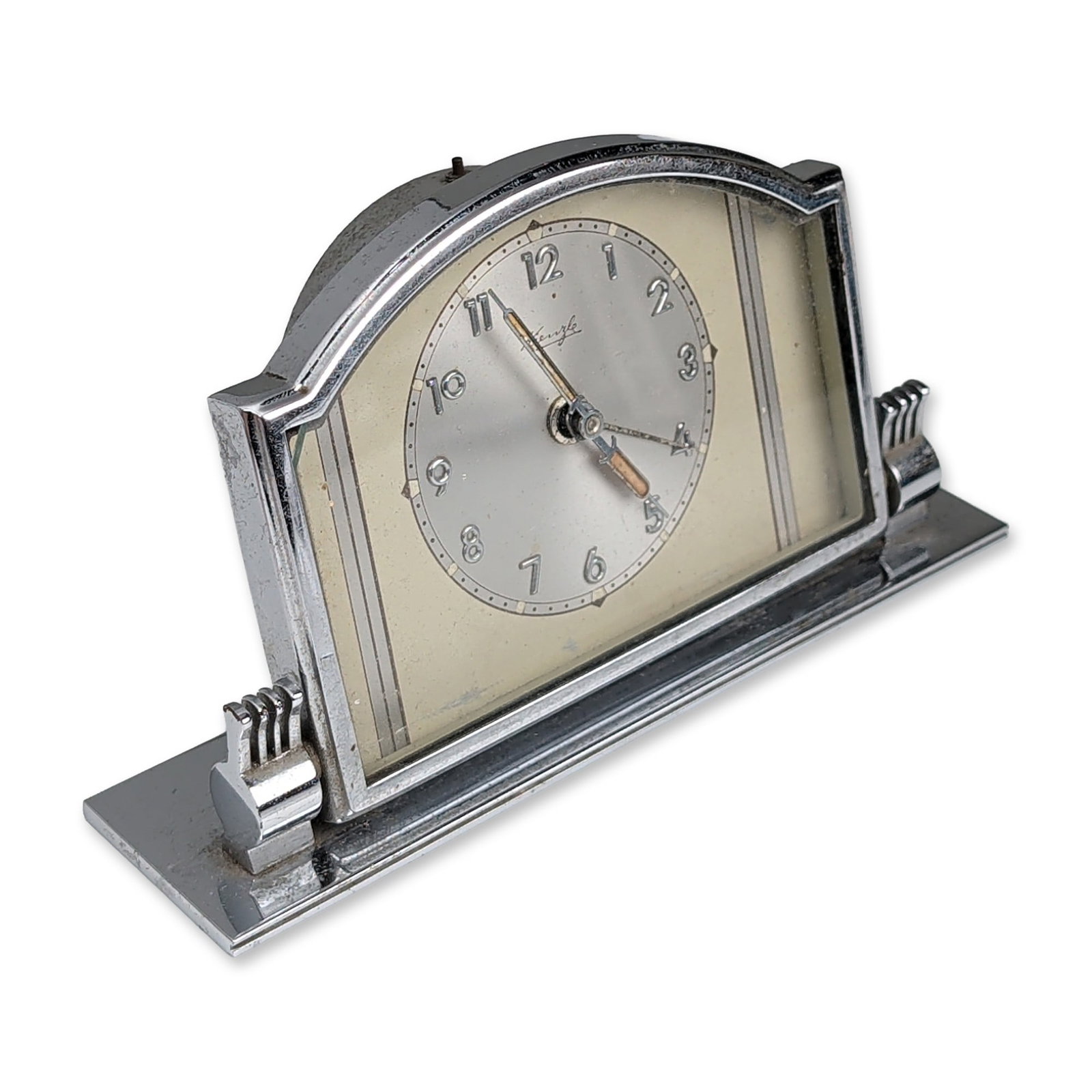 Kienzle Art Deco Chrome Desk Alarm Clock: German Art Deco desk alarm clock by Kienzle. Desk clock in chrome-plated and painted metal, featuring an arched housing with tiered architectural side accents set on a rectangular base. The two-tone s