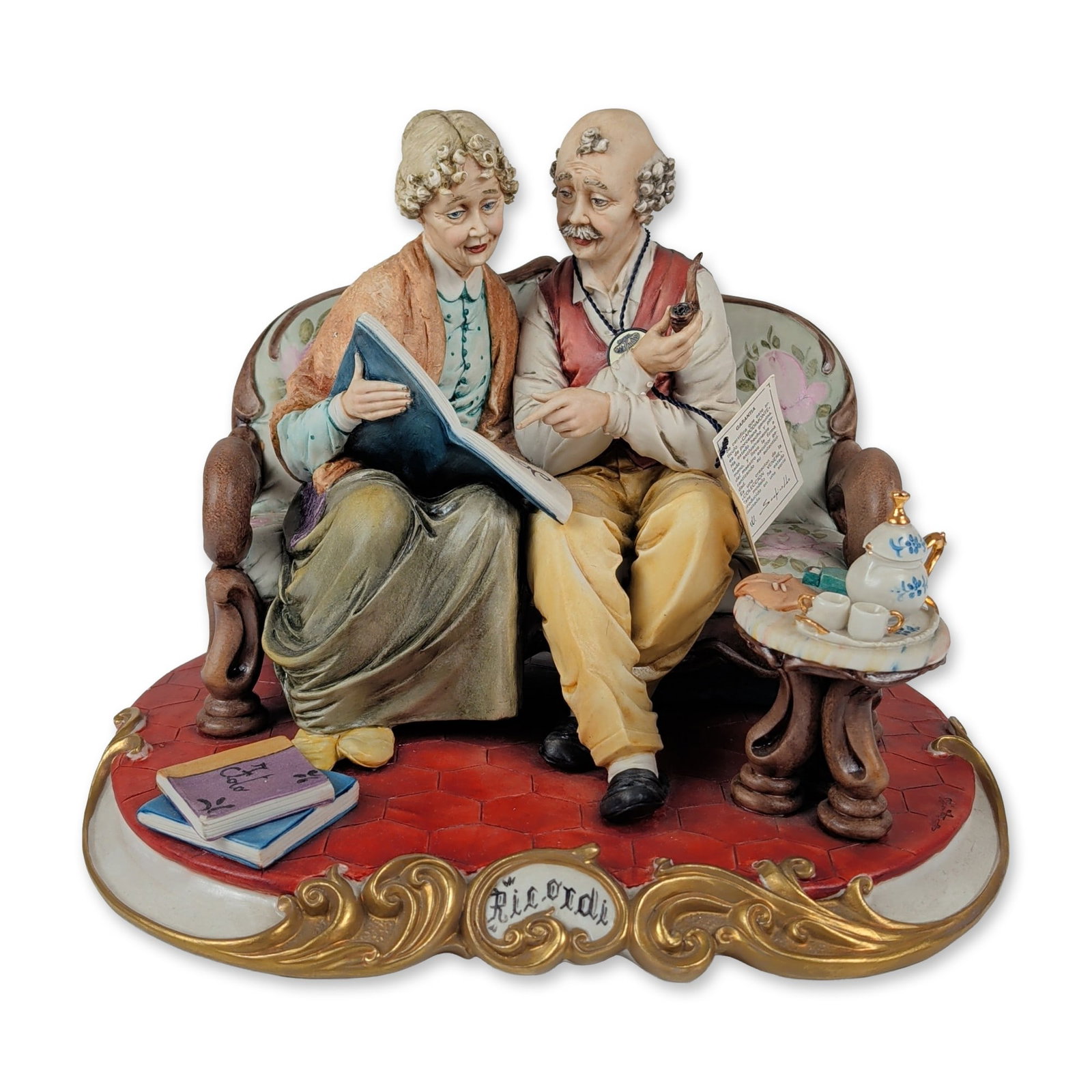 Venere Porcellane d'Arte Capodimonte Ricordi Figurine: Italian hand-painted porcelain figurine group titled Ricordi, depicting an elderly couple on a settee. The matte-finished composition features an elderly man with a smoking pipe and a woman holding an