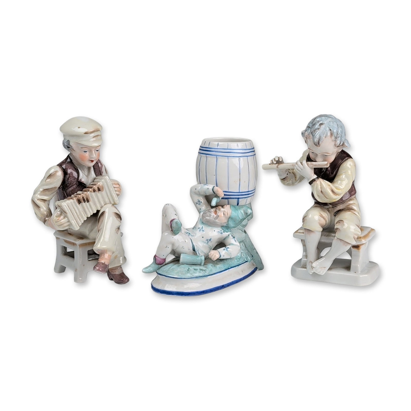 3pc Japanese Porcelain Figurines and Toothpick Holder: Japanese hand-painted glazed porcelain figurine collection including two musicians and a whimsical gnome. The ensemble features a seated boy in a brown vest and white cap playing an accordion on a cha