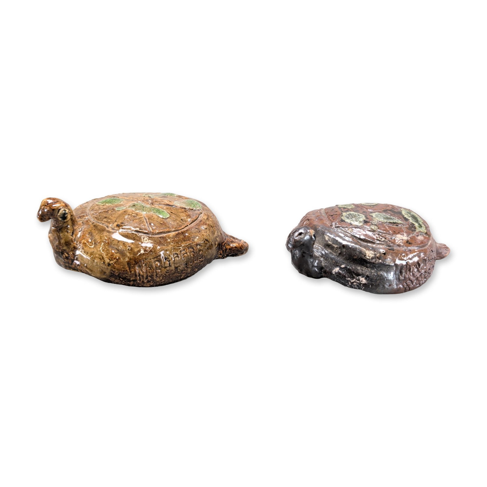 2pc Marie Rogers Pottery Turtles: Pair of turtles in glazed ceramic, each featuring hand-formed bodies with incised shell decoration and green glaze highlights. One turtle is finished in a tan-brown glaze with an upright head, while