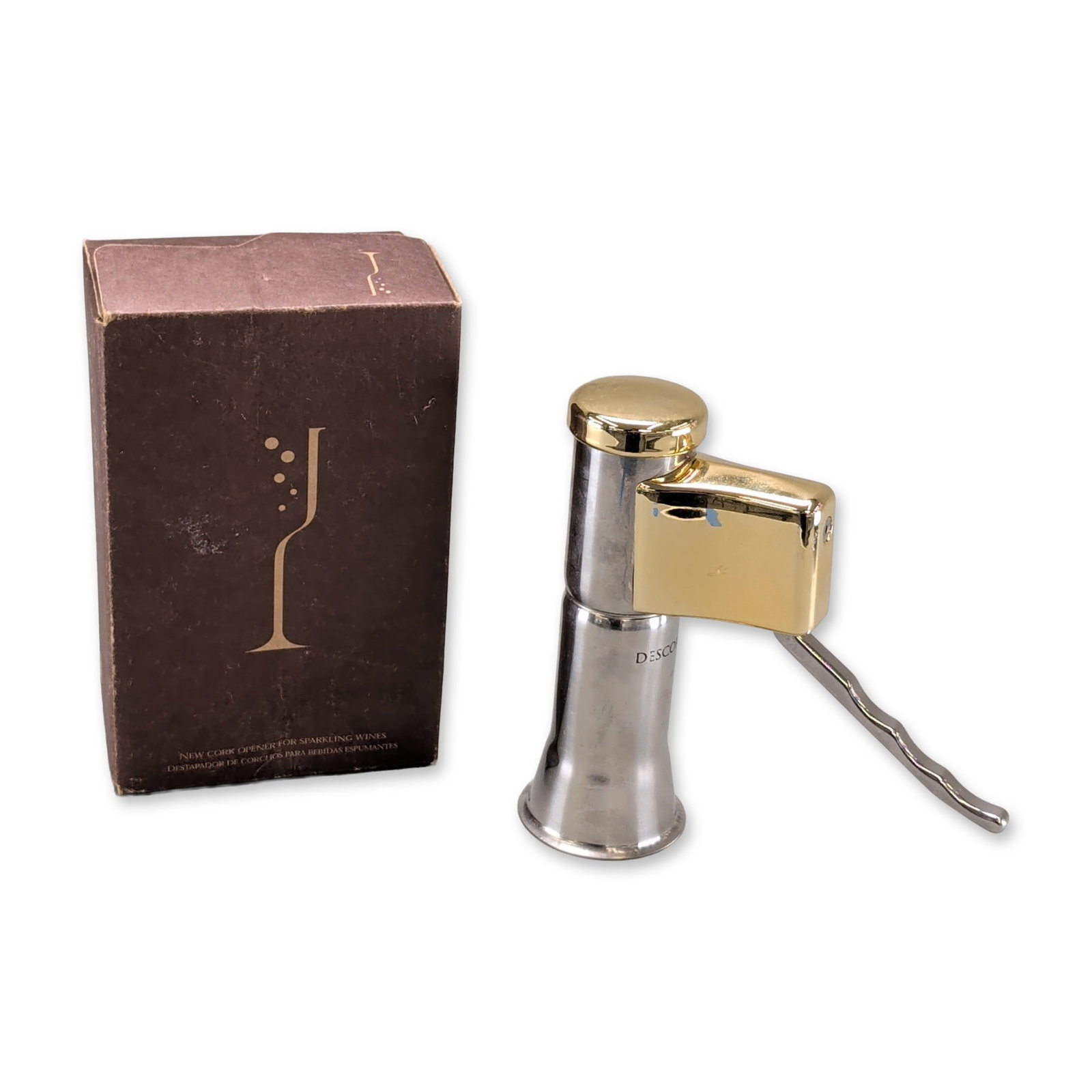 Descorjet Two-Tone Champagne Cork Opener: Descorjet professional champagne cork opener in two-tone silver and gold-toned metal, featuring a flared bell-shaped base, mechanical housing, and a wavy contoured lever handle. The neck is marked wit