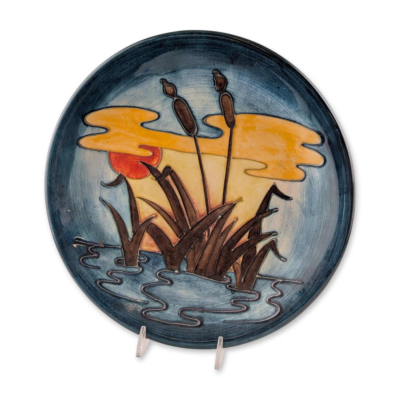 Moorcroft Reeds at Sunset Earthenware Plate: Moorcroft pottery earthenware plate in the Reeds at Sunset pattern, designed by Philip Richardson circa 1980s. The tube-lined decoration depicts stylized dark brown bulrushes and cattails against a gr