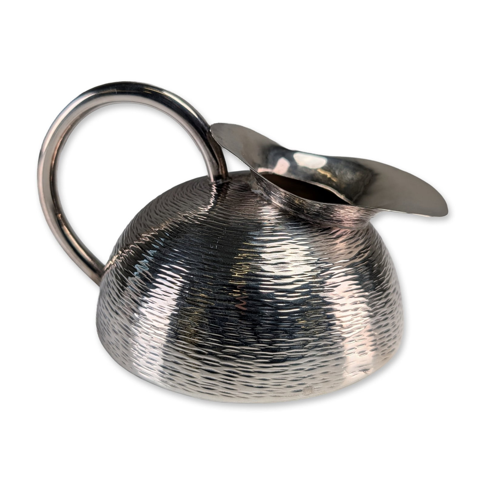 Modernist Solid Silver Martele Creamer: Modernist solid silver creamer featuring a squat hemispherical body with a hand-hammered textured finish. The vessel includes a wide integral pouring spout and a polished C-scroll handle. The base is
