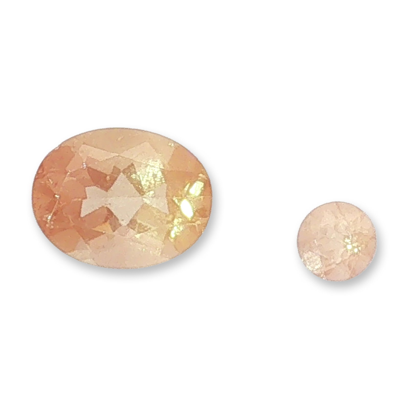 2pc Peachy Pink Loose Gemstones: Pair of unmounted gemstones displaying a delicate peachy-pink hue. The grouping includes one larger oval-cut gemstone and one smaller round brilliant-cut gemstone, both exhibiting good transparency