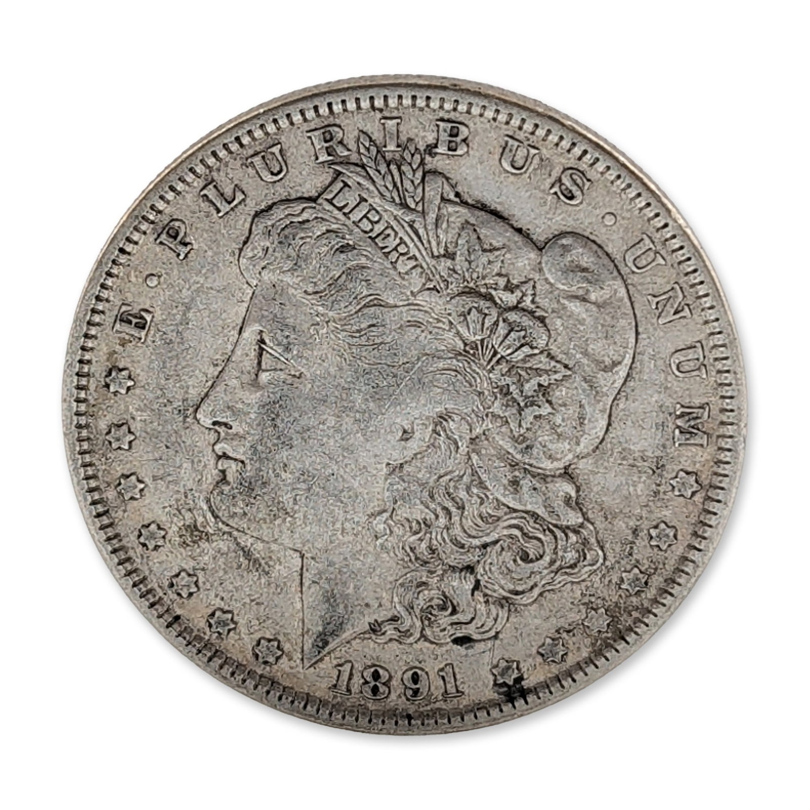 1891 US Morgan Silver Dollar Coin: US 1891 Morgan Silver Dollar. Coin composed of 90% silver and 10% copper, featuring the Liberty Head, facing left obverse design and heraldic eagle reverse. The obverse is struck with a ribbon inscrib