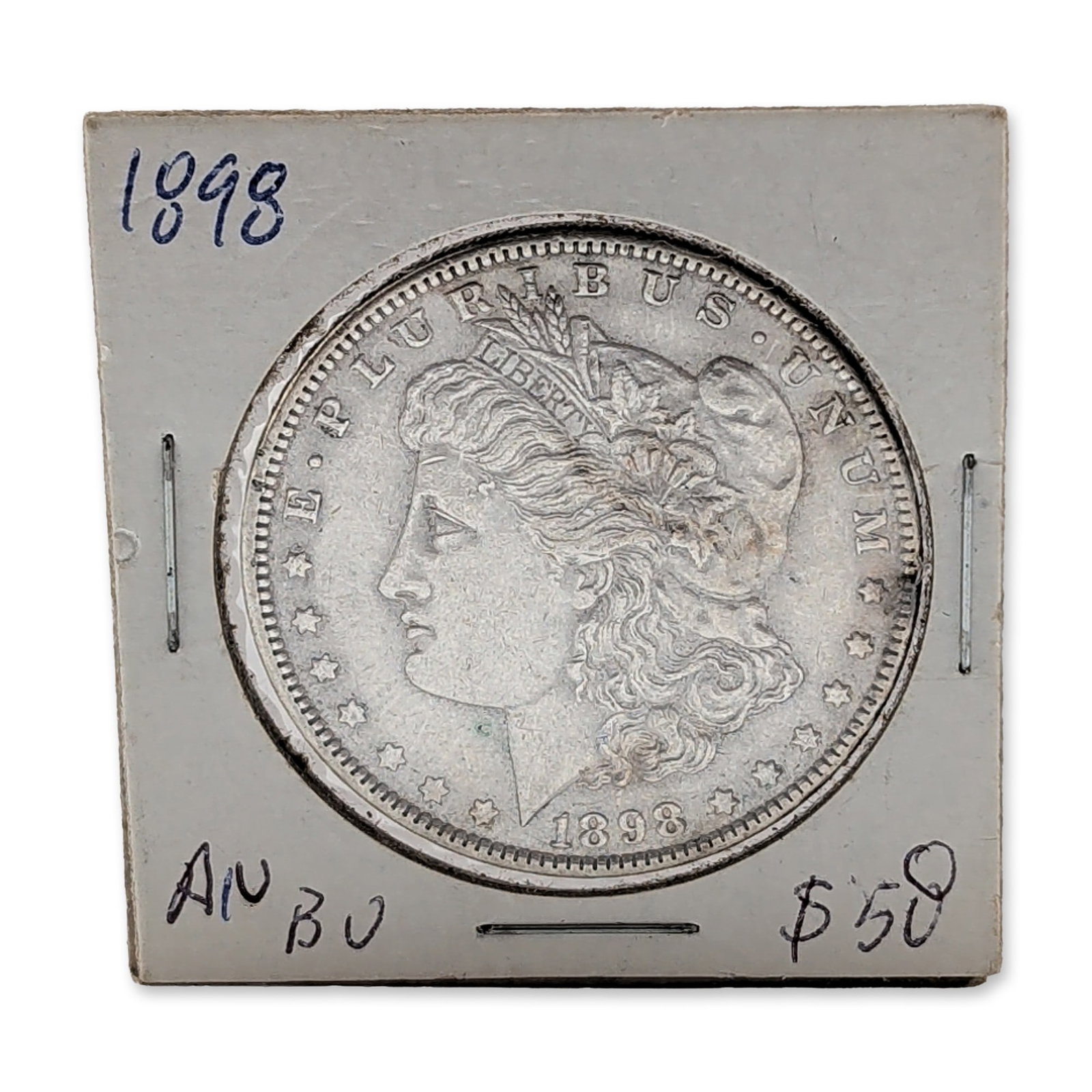 1898 US Morgan Silver Dollar Coin: US 1898 Morgan silver dollar, Philadelphia mint. Coin struck in 90 percent silver featuring the Liberty head obverse and heraldic eagle reverse. The piece is housed in a 2 x 2 cardboard and plastic co