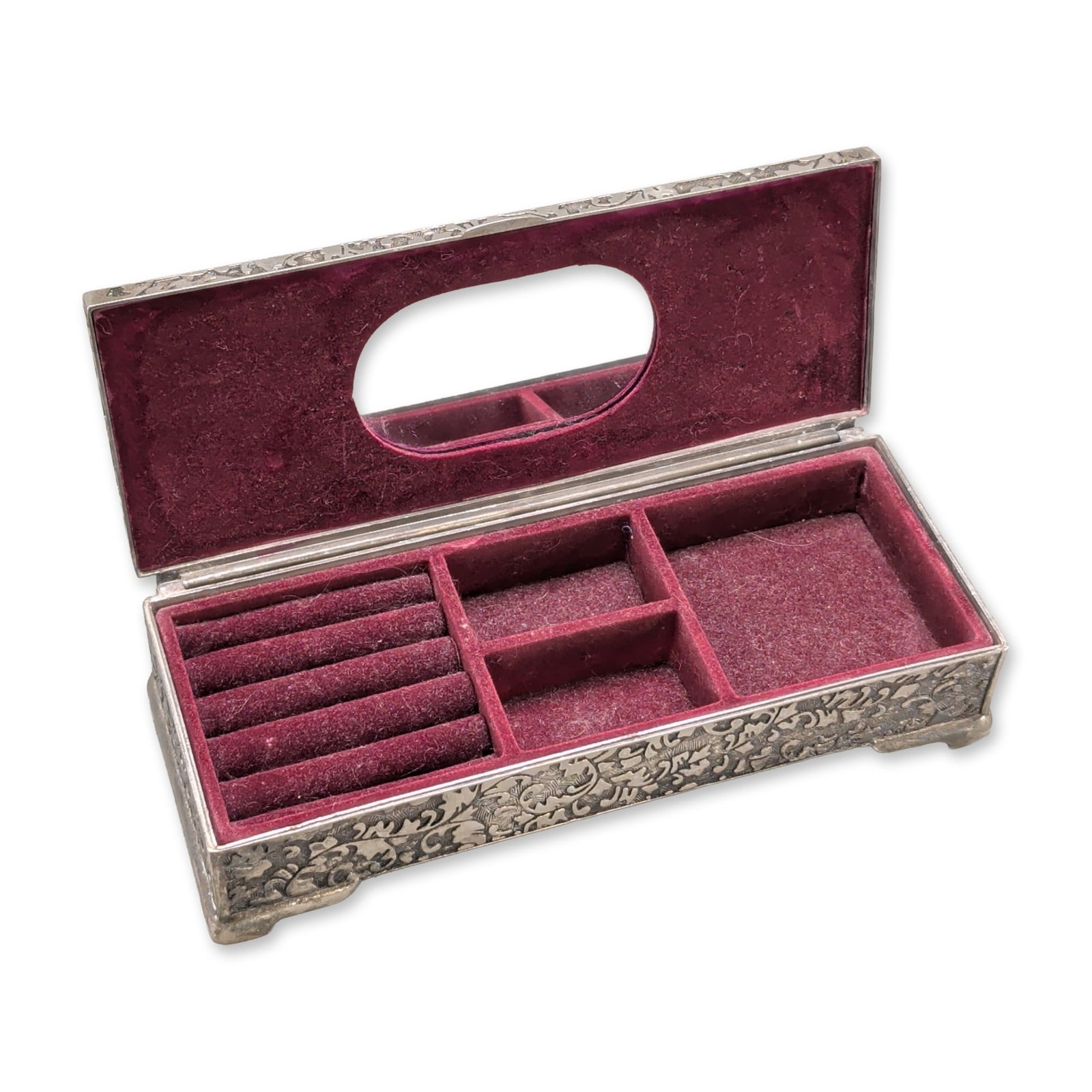 Ornate Repousse Silver Toned Jewelry Box: A rectangular silver-toned metal jewelry box featuring dense repousse and chased decoration with scrolling foliage and floral motifs throughout the exterior. The hinged lid features a central unengrav