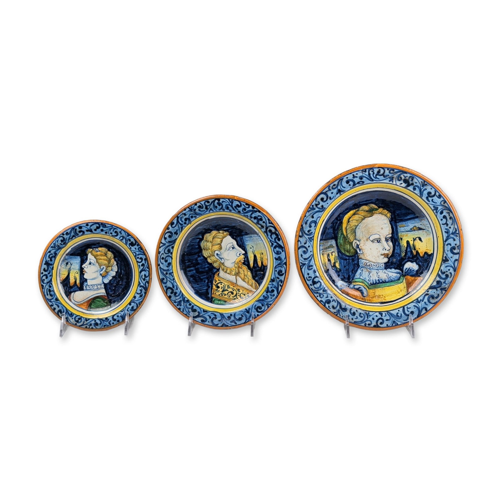 3pc Deruta Italian Majolica Portrait Wall Plates: Trio of graduated portrait plates in glazed earthenware, featuring hand-painted Renaissance-style figures against dark cobalt blue grounds. The central medallions depict profile and three-quarter