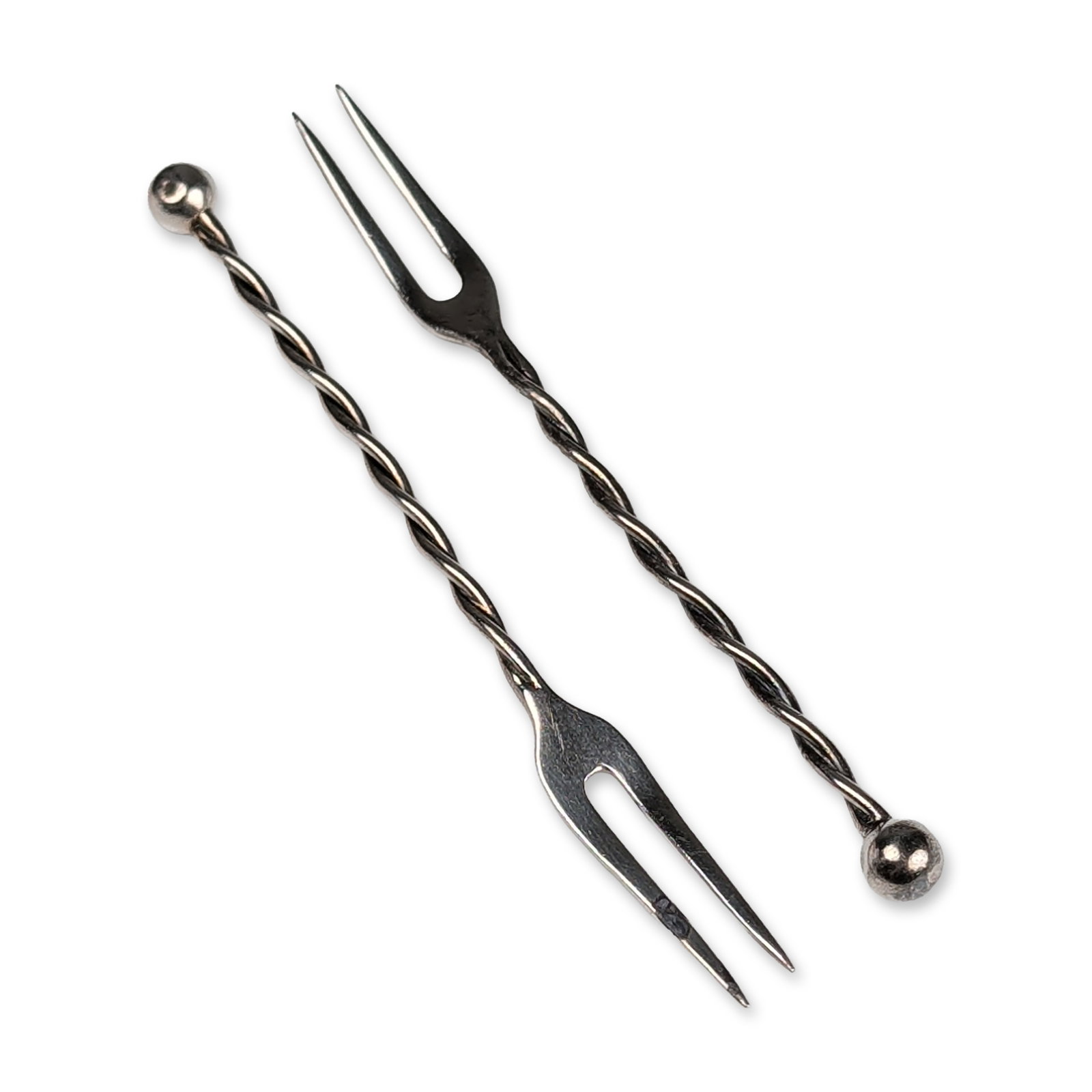 Pair of Mid-century Sterling Silver Twisted Stem Cocktail Forks: Mid-century sterling silver cocktail or appetizer forks. Each piece features a two-tine fork head and a twisted wire stem terminating in a spherical ball finial. Stamped LBS, 925, and Sterling on the