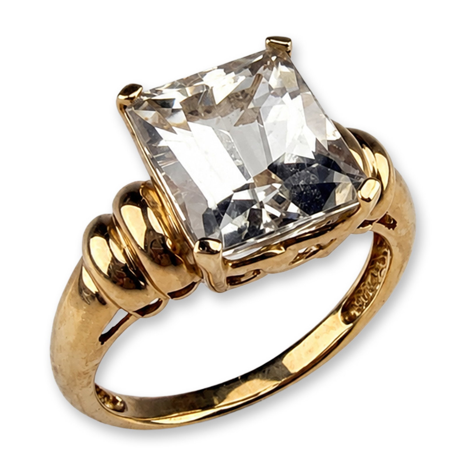 Meda 14K Yellow Gold Emerald Cut Quartz Ring: Meda 14k yellow gold cocktail ring featuring a large rectangular step-cut quartz stone. The stone is secured in a four-prong basket setting above an openwork gallery. The shank is designed with