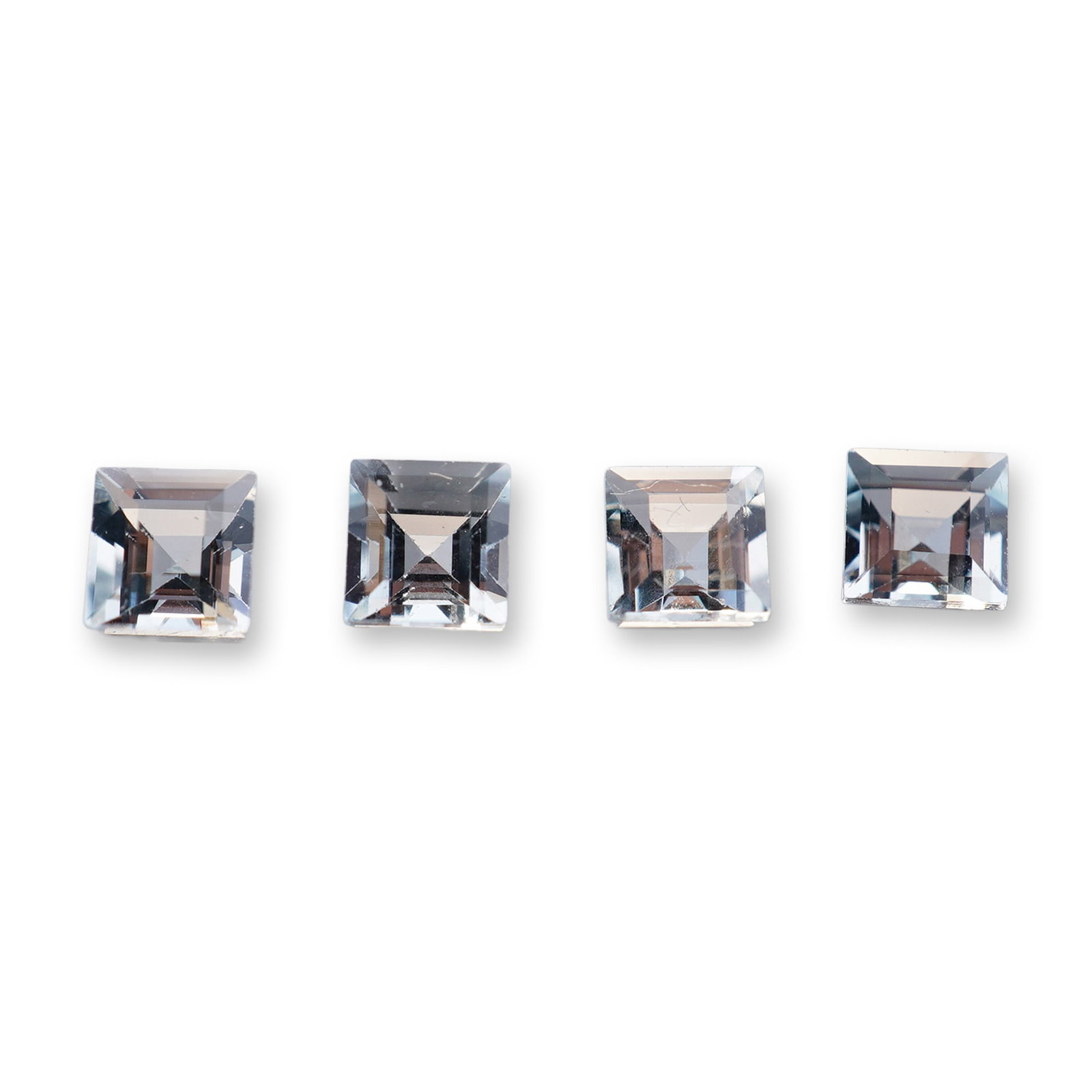 Four Square Cut Aquamarine Gemstones: Set of four matching loose aquamarine gemstones. Each stone is fashioned in a square emerald-cut style featuring step-cut facets and a small table. The gemstones exhibit a uniform pale blue color and
