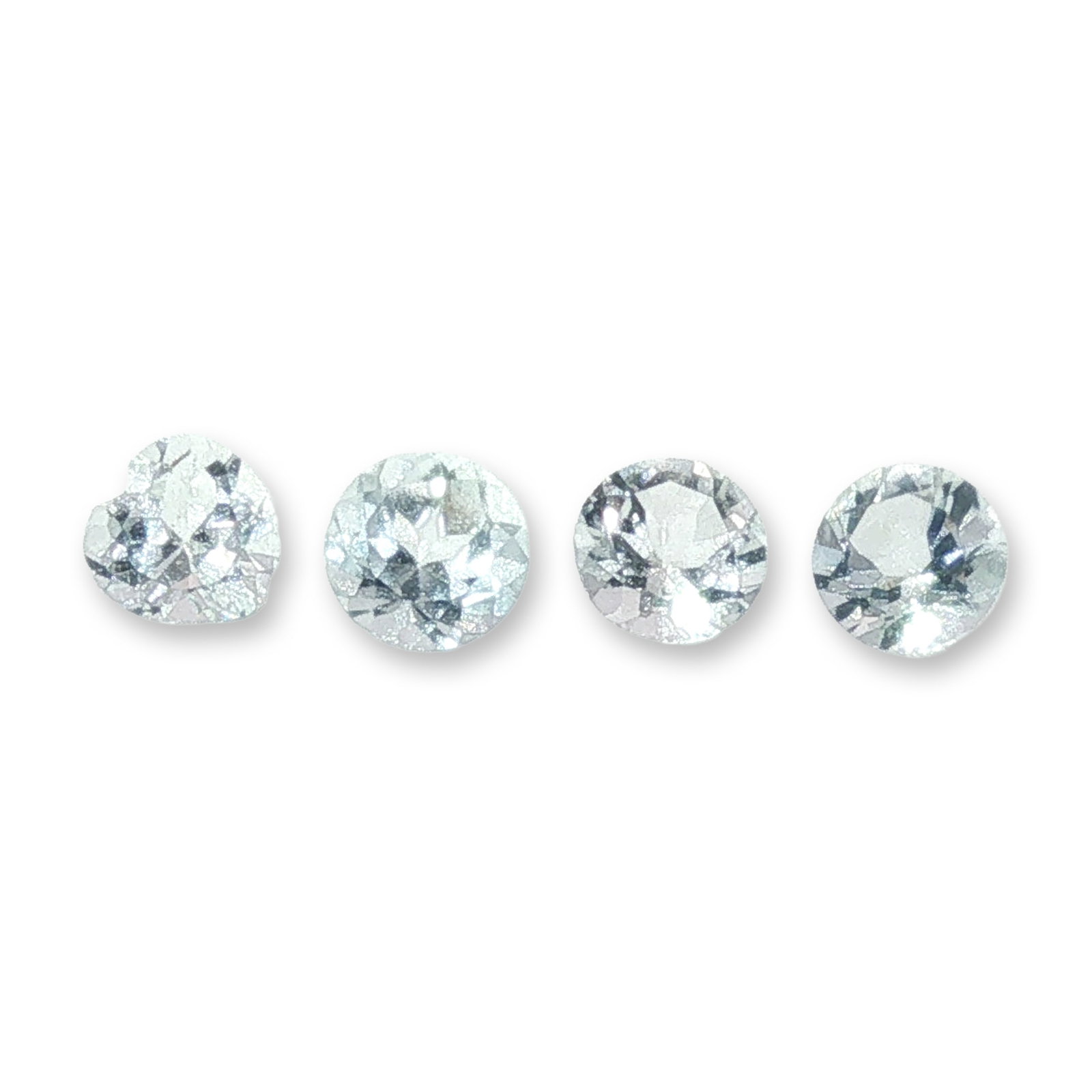 Set of Four Loose Aquamarine Gemstones: Set of four loose gemstones appearing to be aquamarine. Each stone features a pale icy blue hue and faceted construction, including one heart-cut stone and three round-cut stones. These gems are