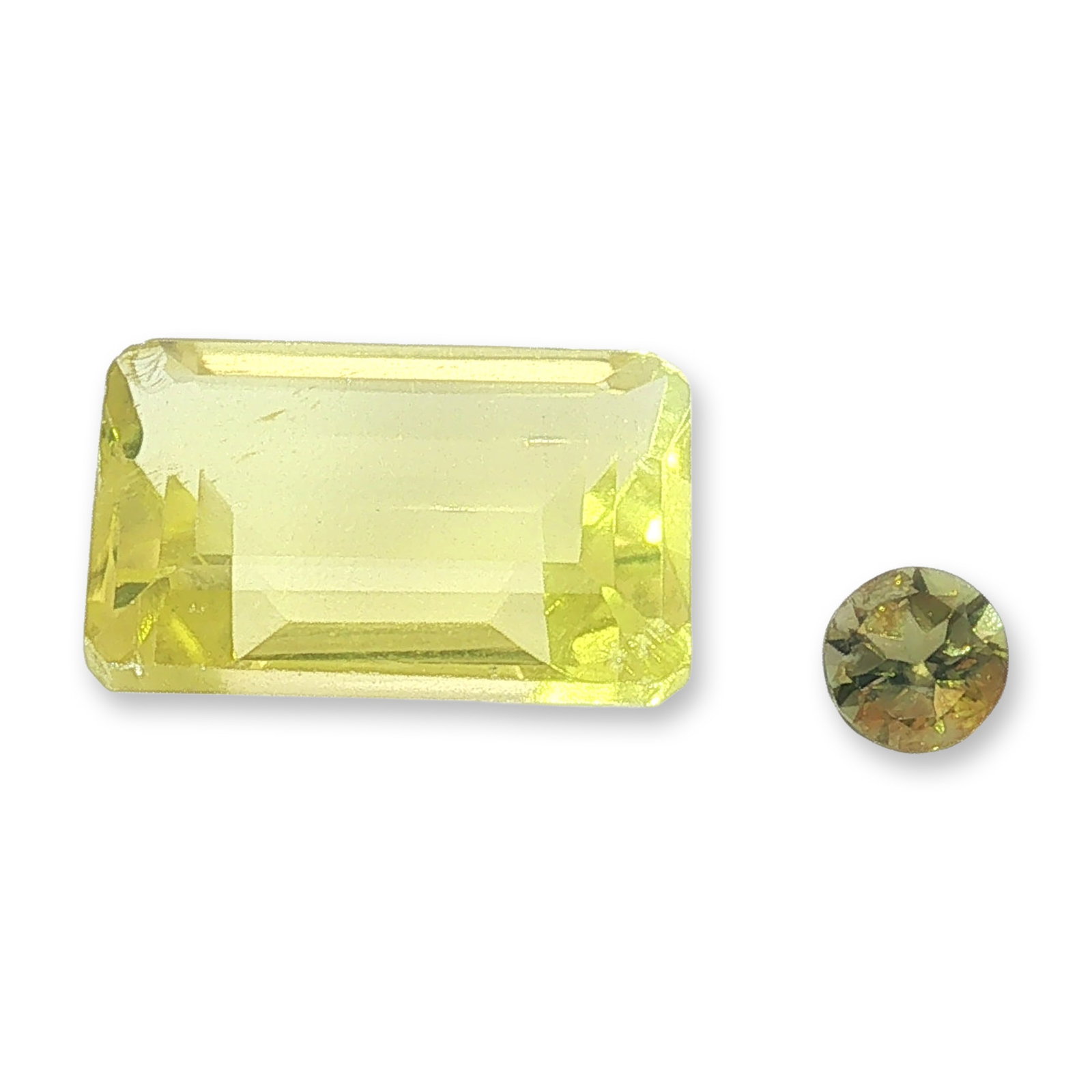 Two Loose Lemon Citrine and Chrysoberyl Gemstones: Two loose gemstones including one lemon citrine and one chrysoberyl. The larger stone appears to be a lemon citrine in an emerald cut, featuring a light yellow hue and internal linear inclusions or ve