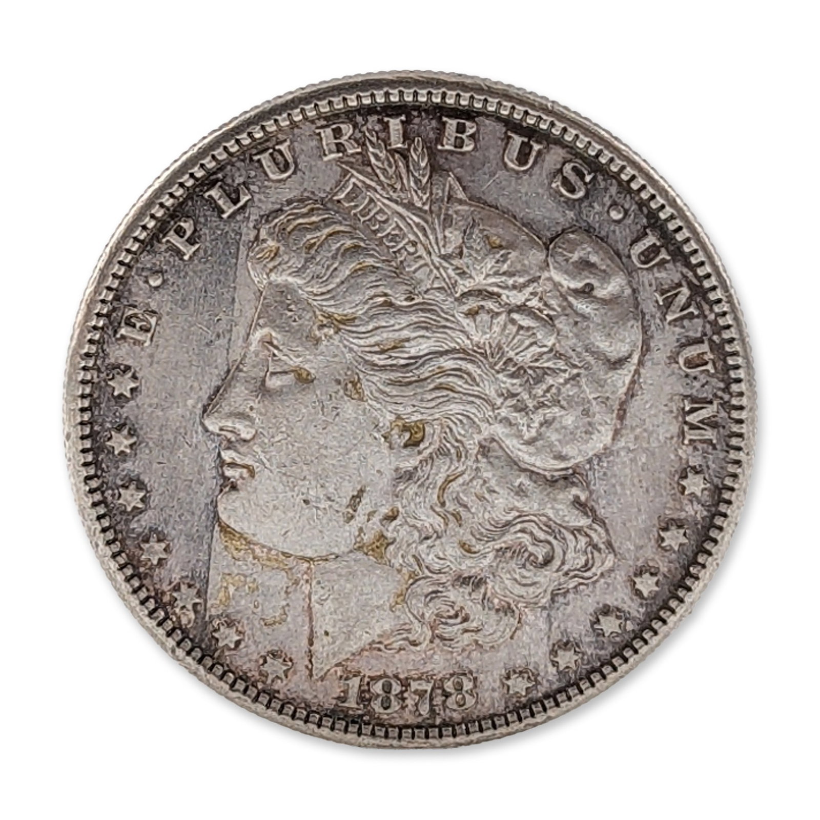 1878-S US Morgan Silver Dollar Coin: 1878-S US Morgan silver dollar, 7-tail-feather variety, San Francisco Mint. Composed of 90 percent silver and 10 percent copper. The obverse features a profile of Liberty wearing a cap inscribed LIBER