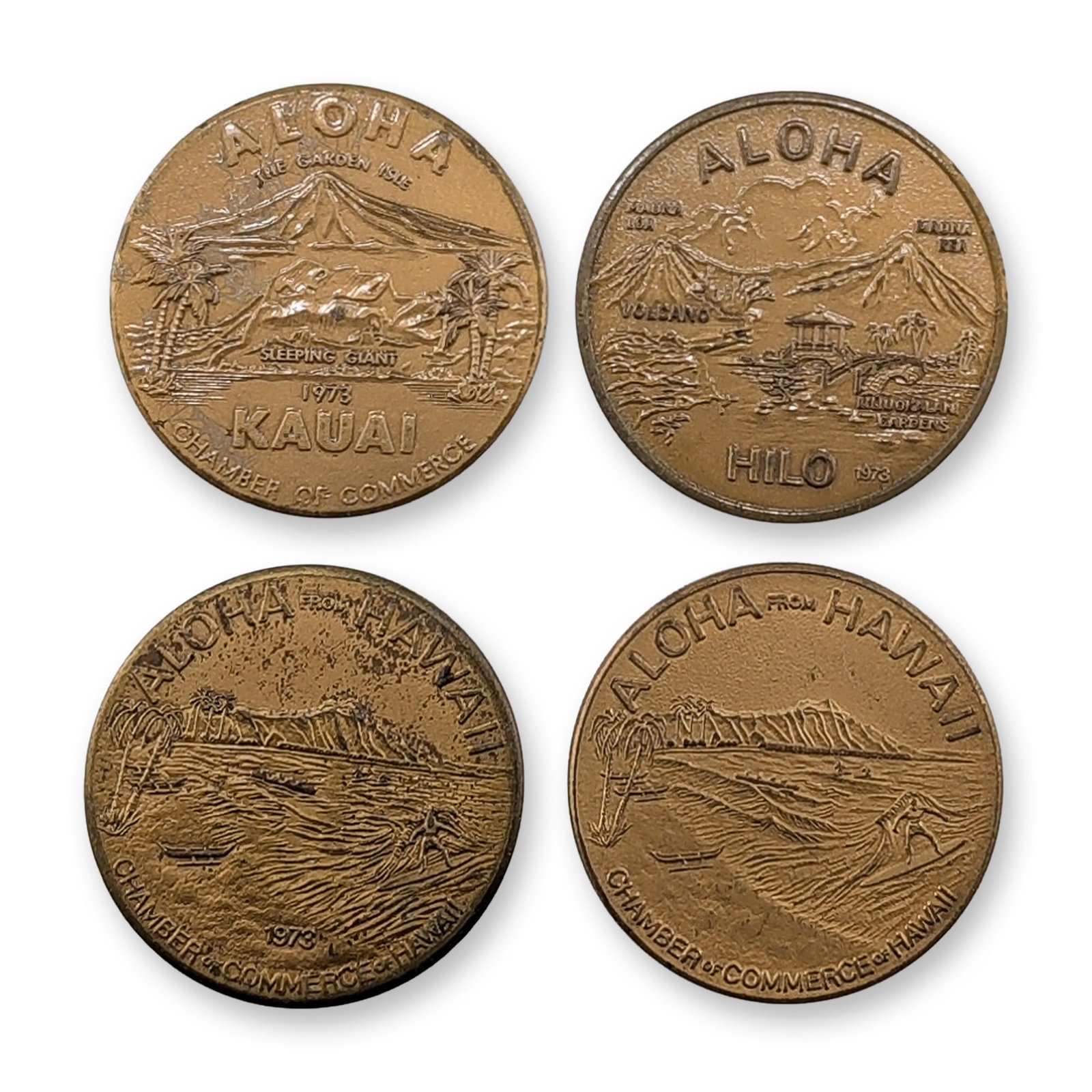 4pc 1973 & 1976 Hawaii Chamber of Commerce Brass Souvenir Dollars: Group of Hawaii Chamber of Commerce souvenir dollars in brass metal, featuring regional designs for Kauai, Hilo, and Honolulu. The Kauai issue depicts a Prince Kuhio portrait and a mountain landscape 