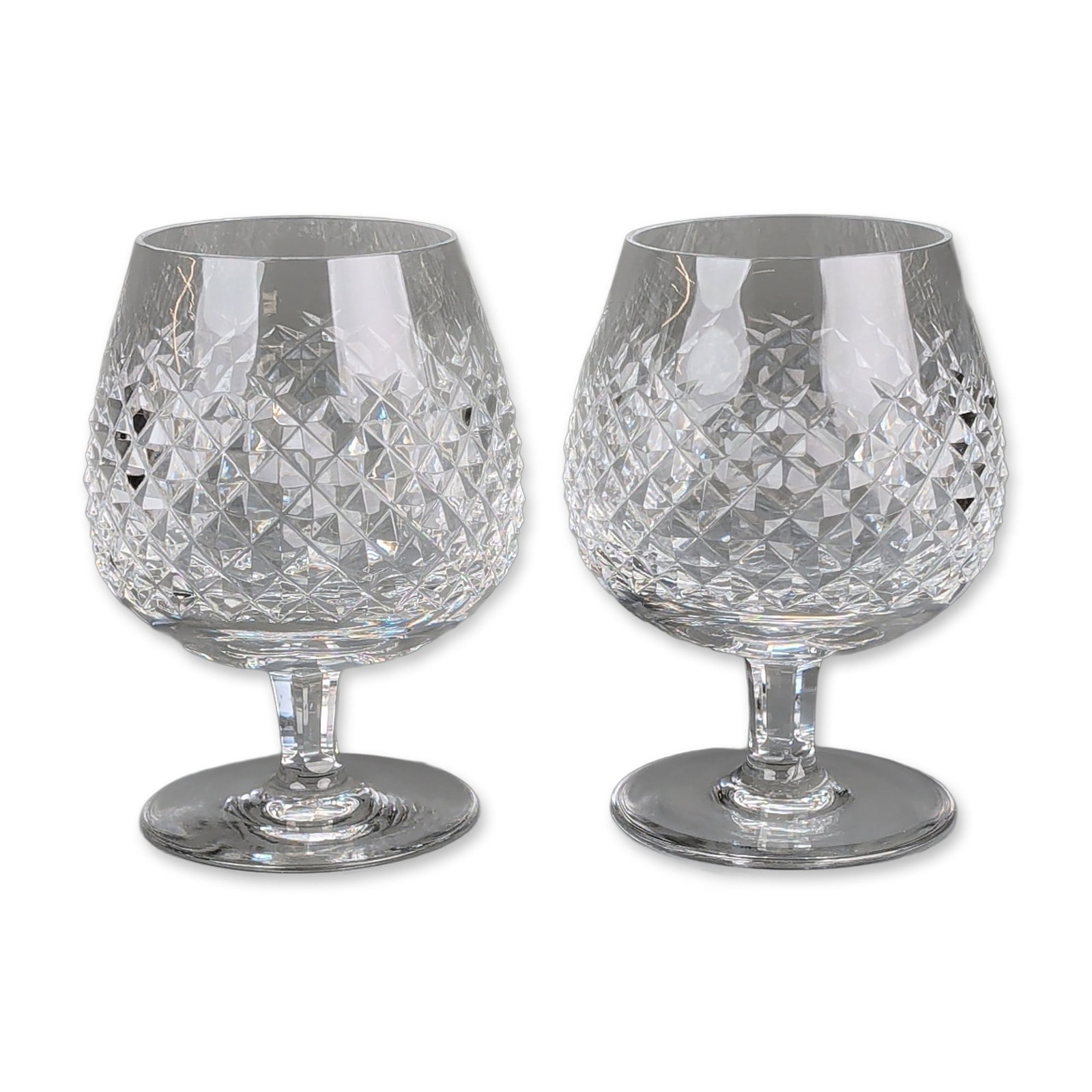 Pair of Waterford Crystal Brandy Snifters, Alana Pattern: Waterford. Pair of brandy snifters in cut crystal, featuring the Alana pattern with bulbous bowls decorated with deep diamond-quilted cutting. Each piece has a faceted hexagonal stem and a plain circu