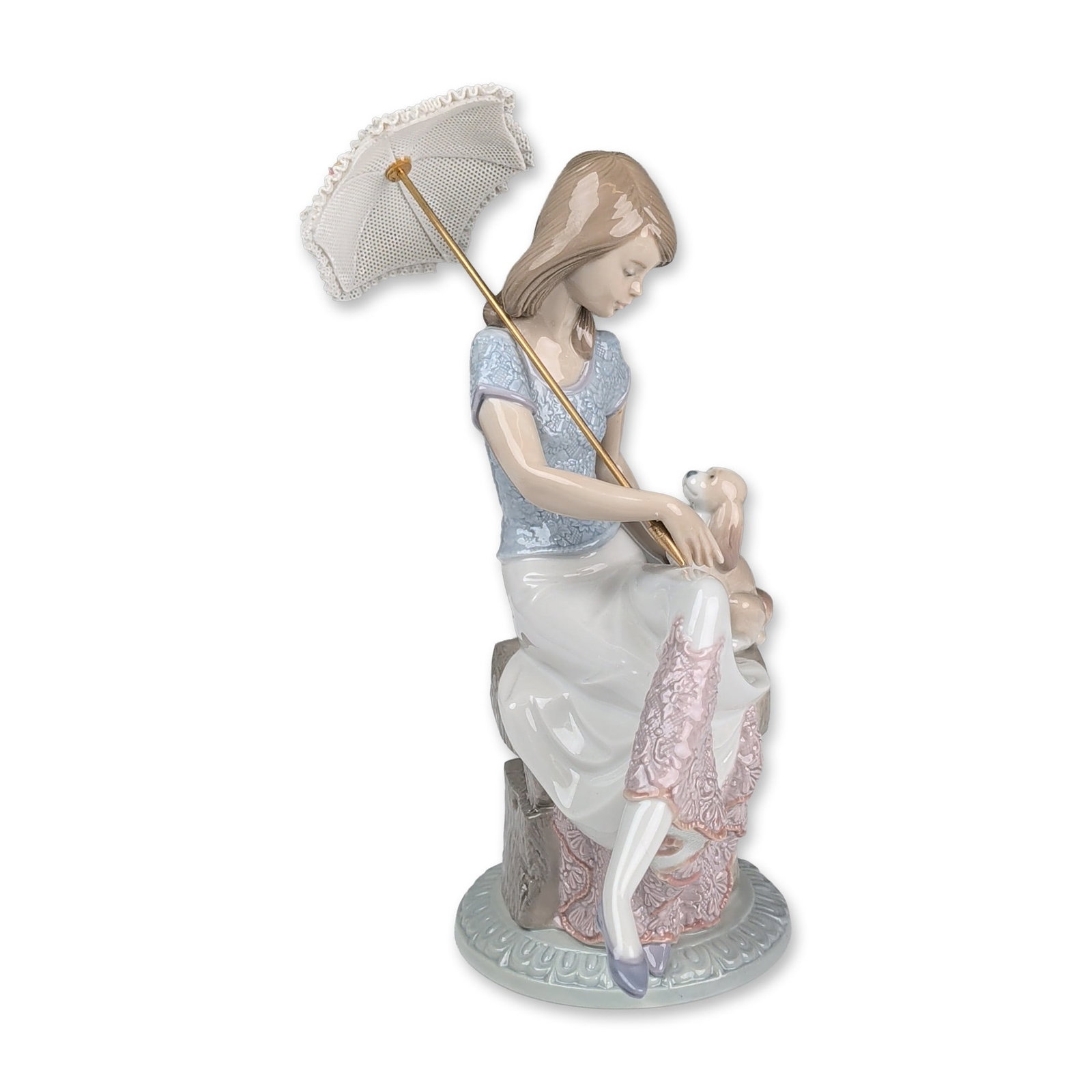Lladro Porcelain Figurine, Picture Perfect 1007612: Depicting a young girl seated on a stone-textured plinth while holding a puppy and a parasol. The figure features a light blue floral-textured bodice and a white skirt with pink porcelain lace trim at