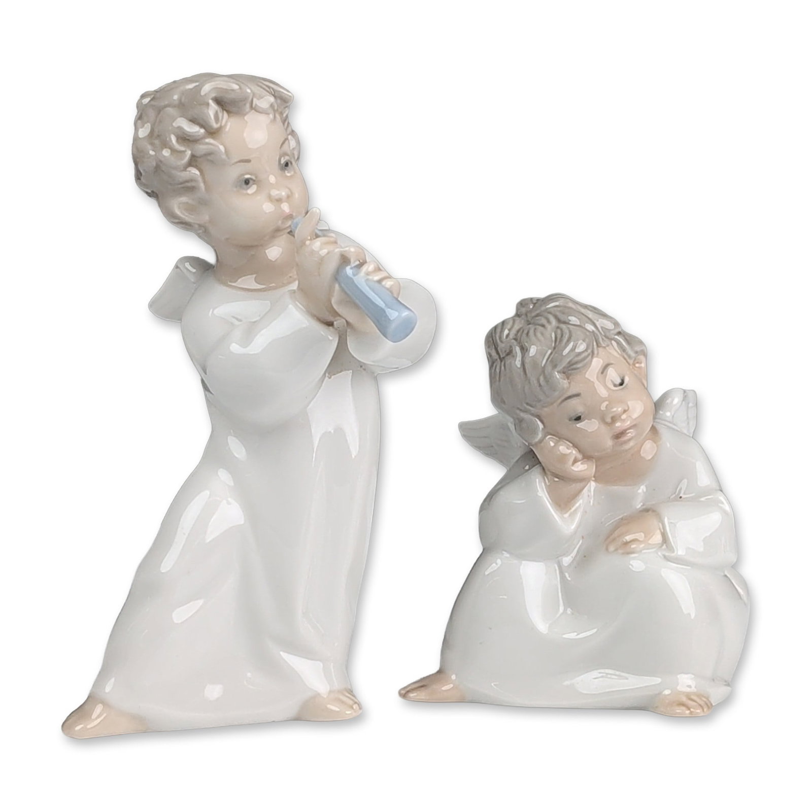 2pc Lladro Glazed Porcelain Angel Figurines, Angel With Flute 01004540 & Angel Thinking 01004539: Porcelain figurines depicting cherubic angels. One figure depicts a standing angel in a white robe playing a light blue flute, and the second depicts a seated angel in a pensive pose with head resting