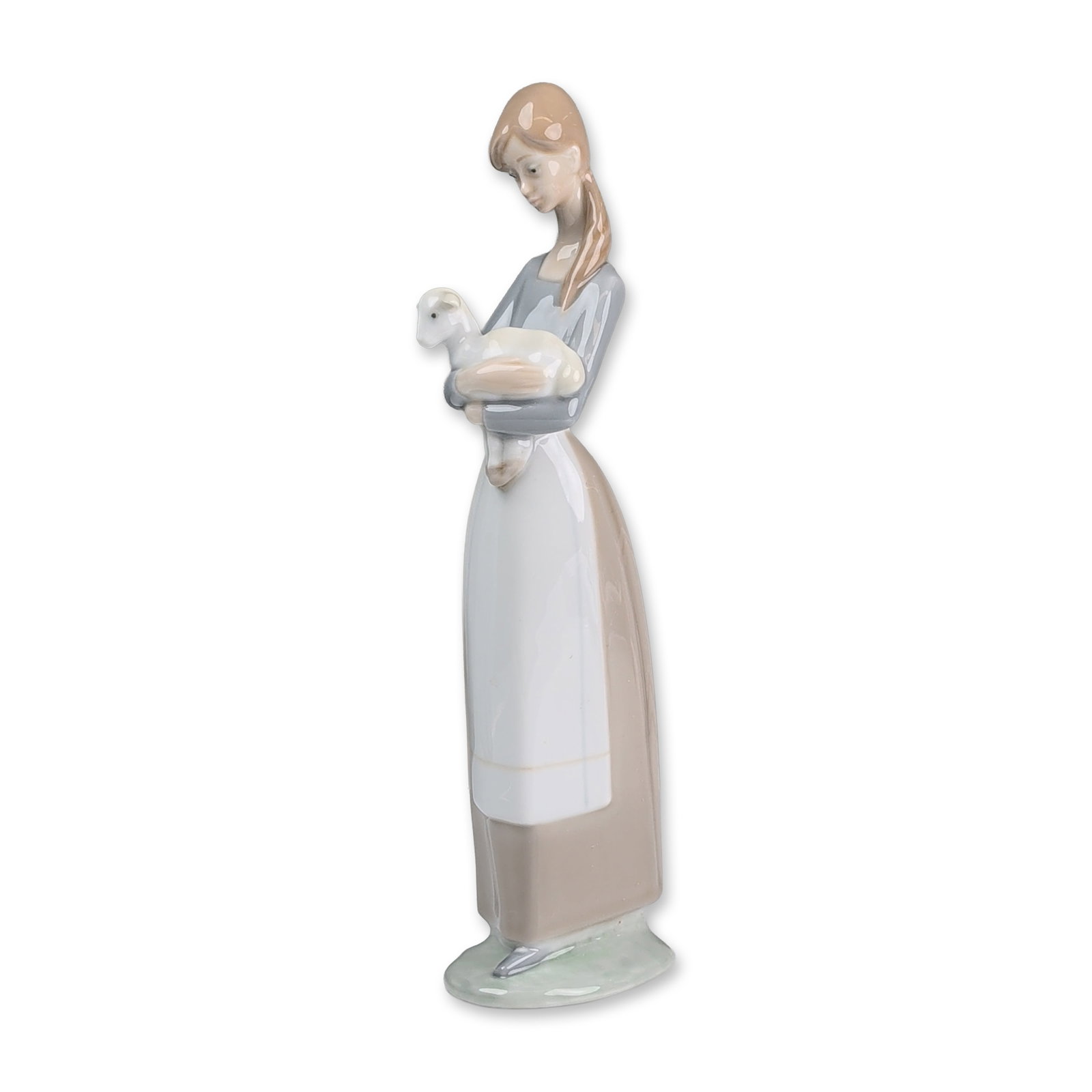 Lladro Glazed Porcelain Figurine, Girl with Lamb 01004505: Porcelain figurine depicting a young girl with long hair wearing a grey bodice and a long tan and white skirt, cradling a white lamb. The underside of the base features a blue printed logo of a bell a