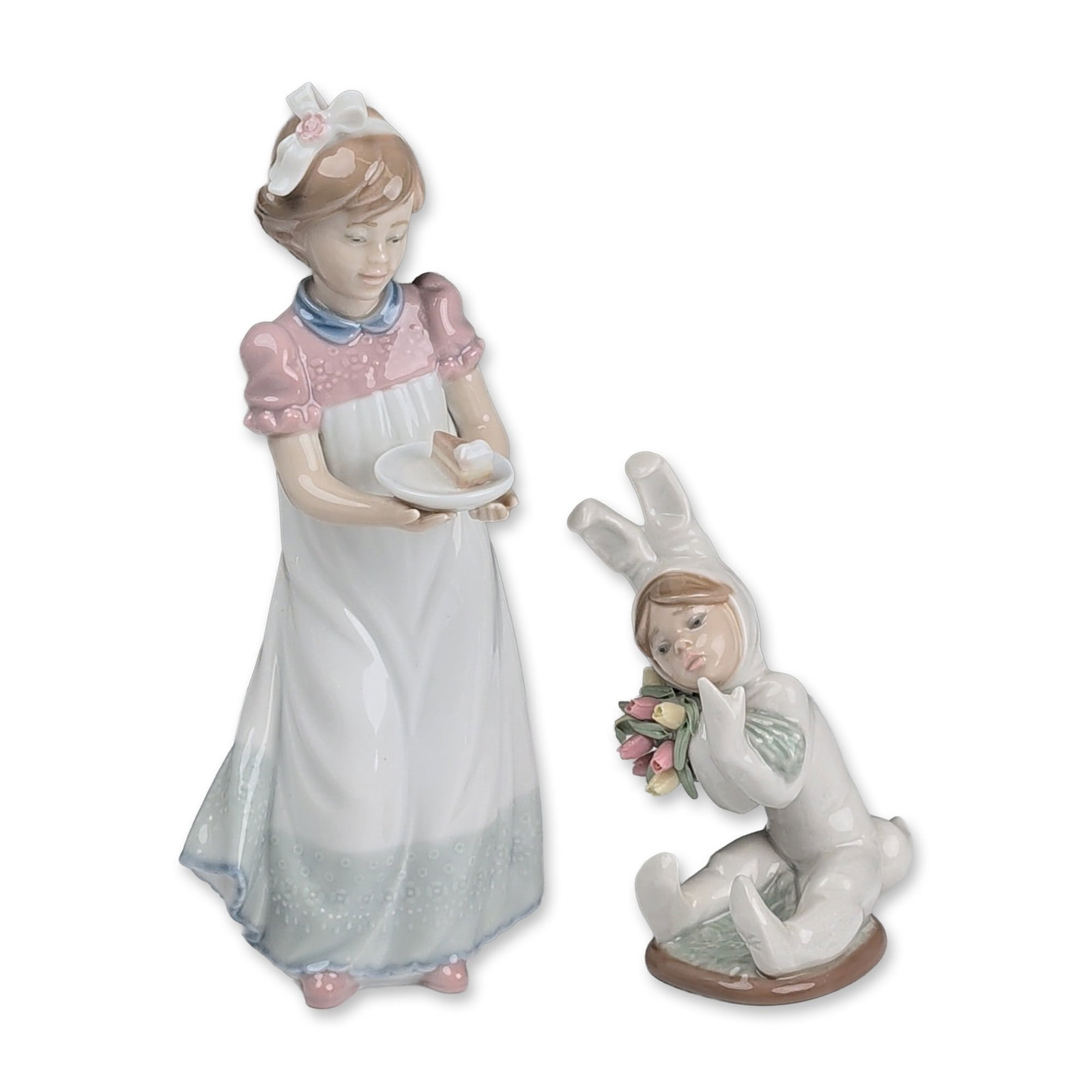 2pc Lladro Porcelain Figurines, Happy Birthday 01005429 & Spring Flowers 01001509: Lladro Spanish glazed porcelain figurines depicting childhood subjects. The group includes a figurine of a girl wearing a pink bodice and a white skirt with a blue floral hem, holding a plate with a s