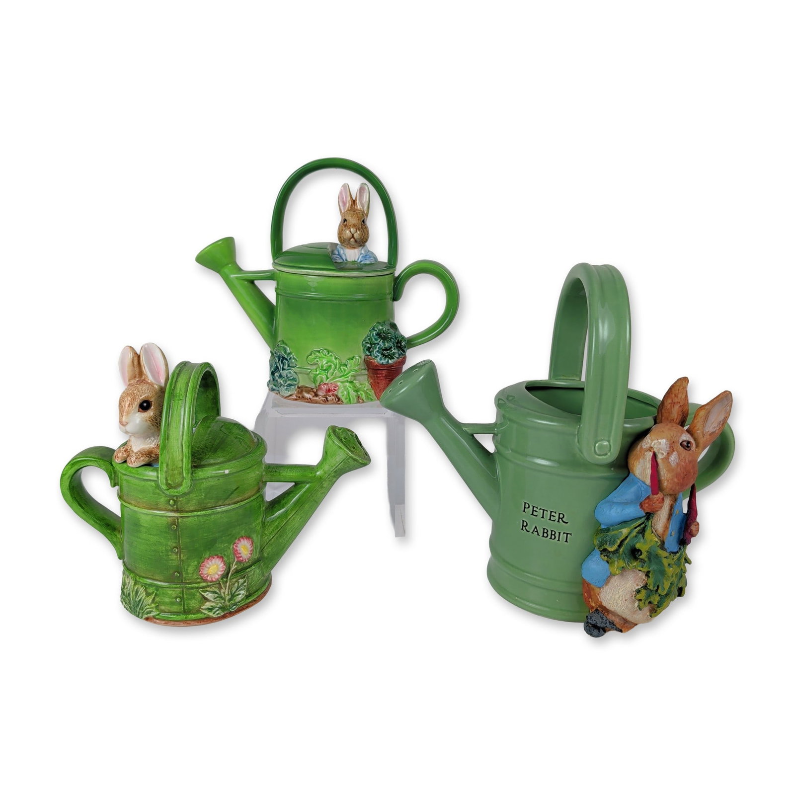 3pc Beatrix Potter Peter Rabbit Ceramic Watering Cans: Beatrix Potter series. Group of three decorative ceramic watering cans in glazed earthenware by Enesco, Schmid, and Teleflora Gift. The first example features a textured wood-plank form with molded ri