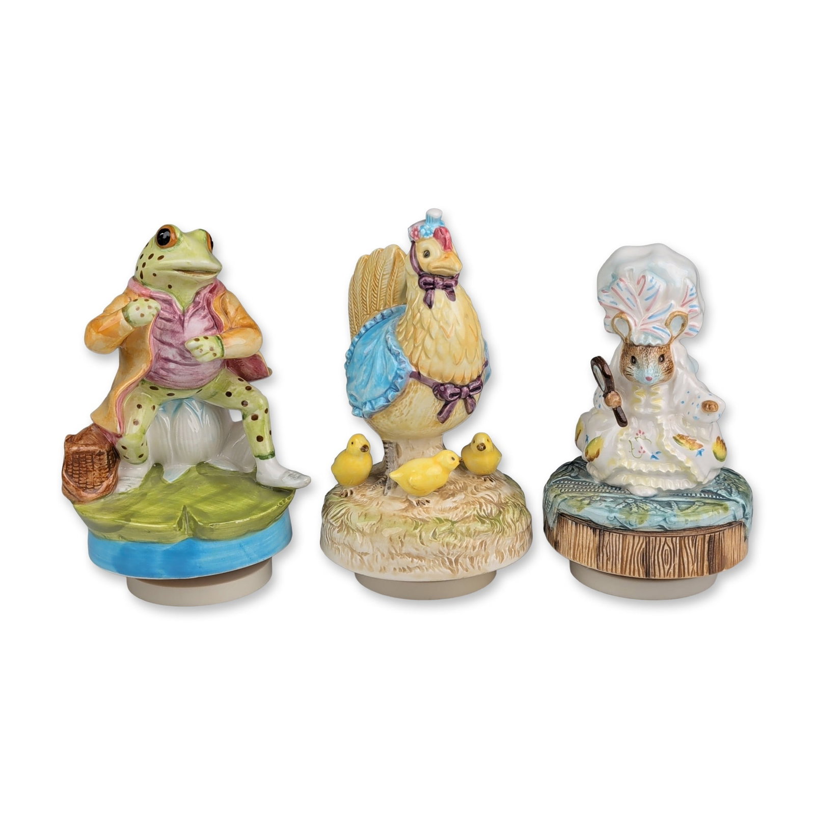 3pc Schmid Beatrix Potter Ceramic Musical Figurines: The grouping includes Mr. Jeremy Fisher depicted as a frog in a yellow coat and pink waistcoat seated on a lily pad; Jemima Puddle-Duck wearing a blue shawl and pink bonnet standing over three ducklin