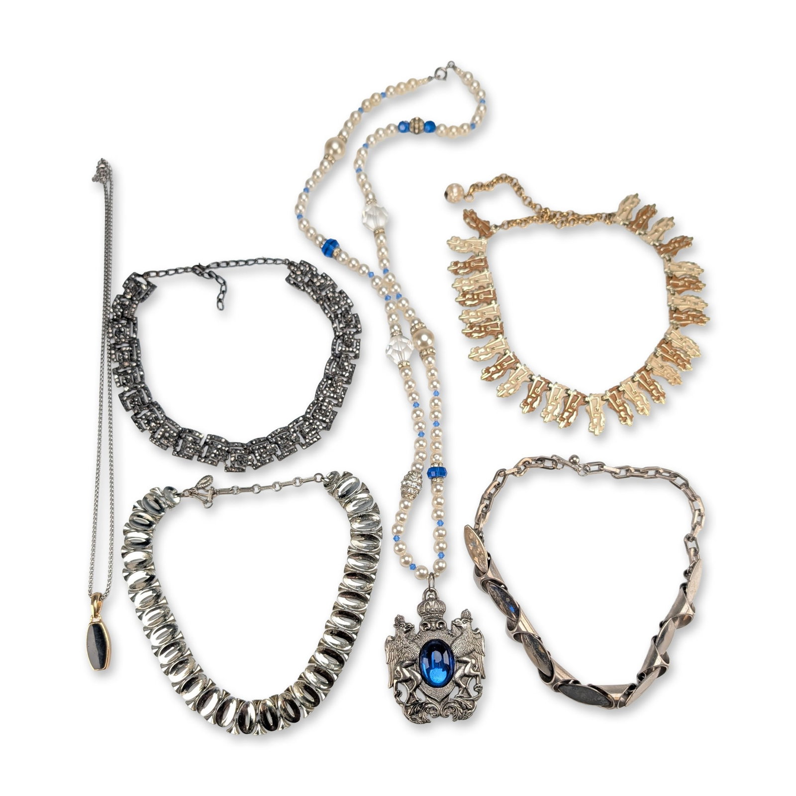 6pc Vintage Costume Jewelry Collection: Collection of six vintage costume jewelry necklaces in various styles and metal finishes. The group includes a silver-tone collar necklace composed of oval and cone-like links. A heraldic-style lariat