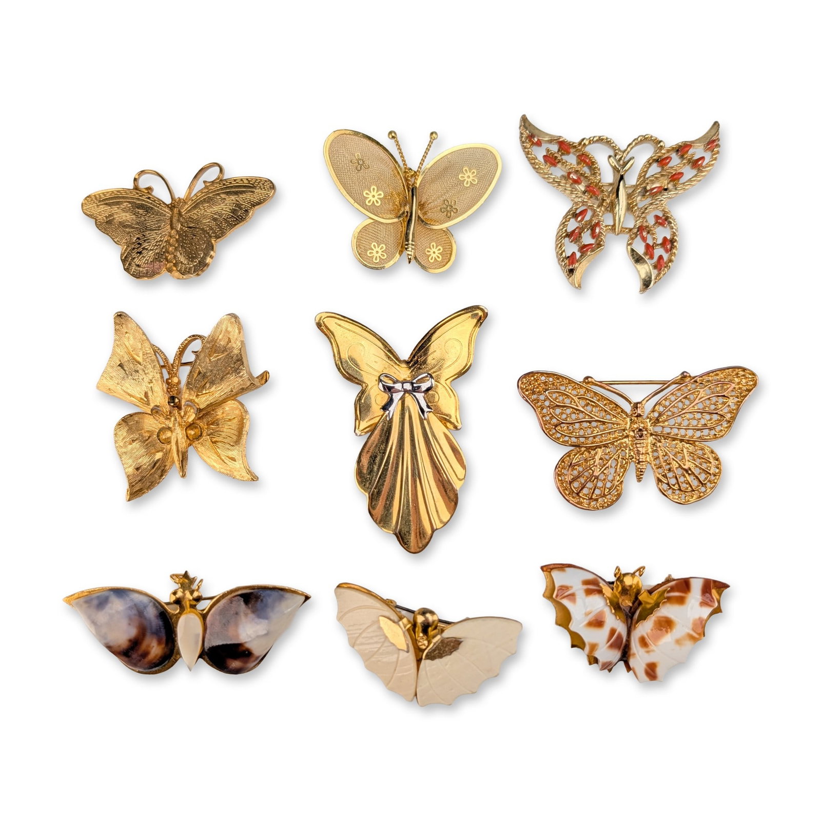 9pc Collection of Gold-Toned Butterfly Brooches: Collection of nine gold-toned base metal butterfly brooches in assorted styles, including filigree, mesh, and shell-inlay examples. A brooch with textured wings and a grid-patterned reverse. A stylize