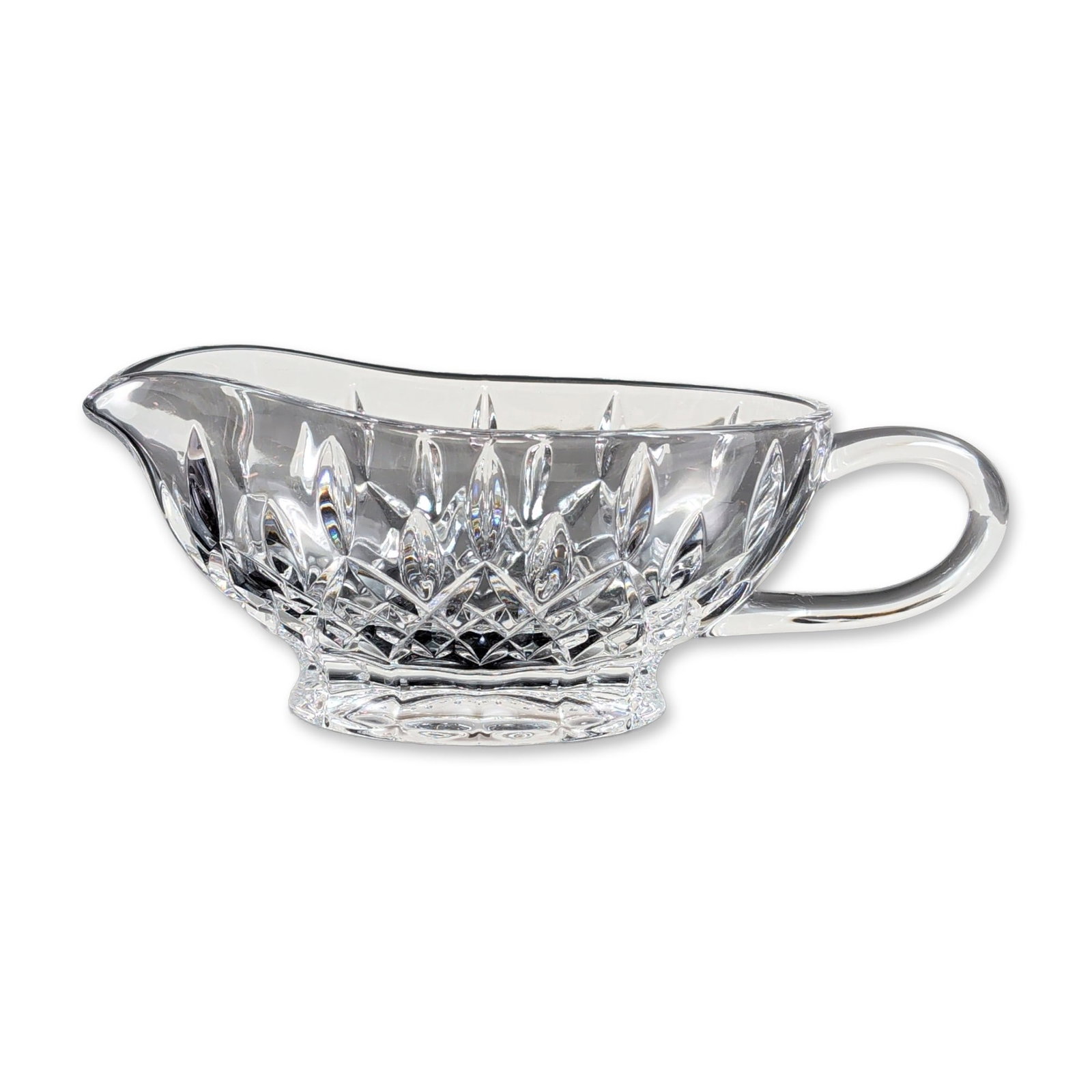 Waterford Crystal Lismore Pattern Sauce Boat: Crystal sauce boat featuring a pinched pouring spout and an applied clear C-scroll handle. The vessel is decorated with a band of deep-cut cross-hatched diamonds beneath radiating vertical wedge cuts 