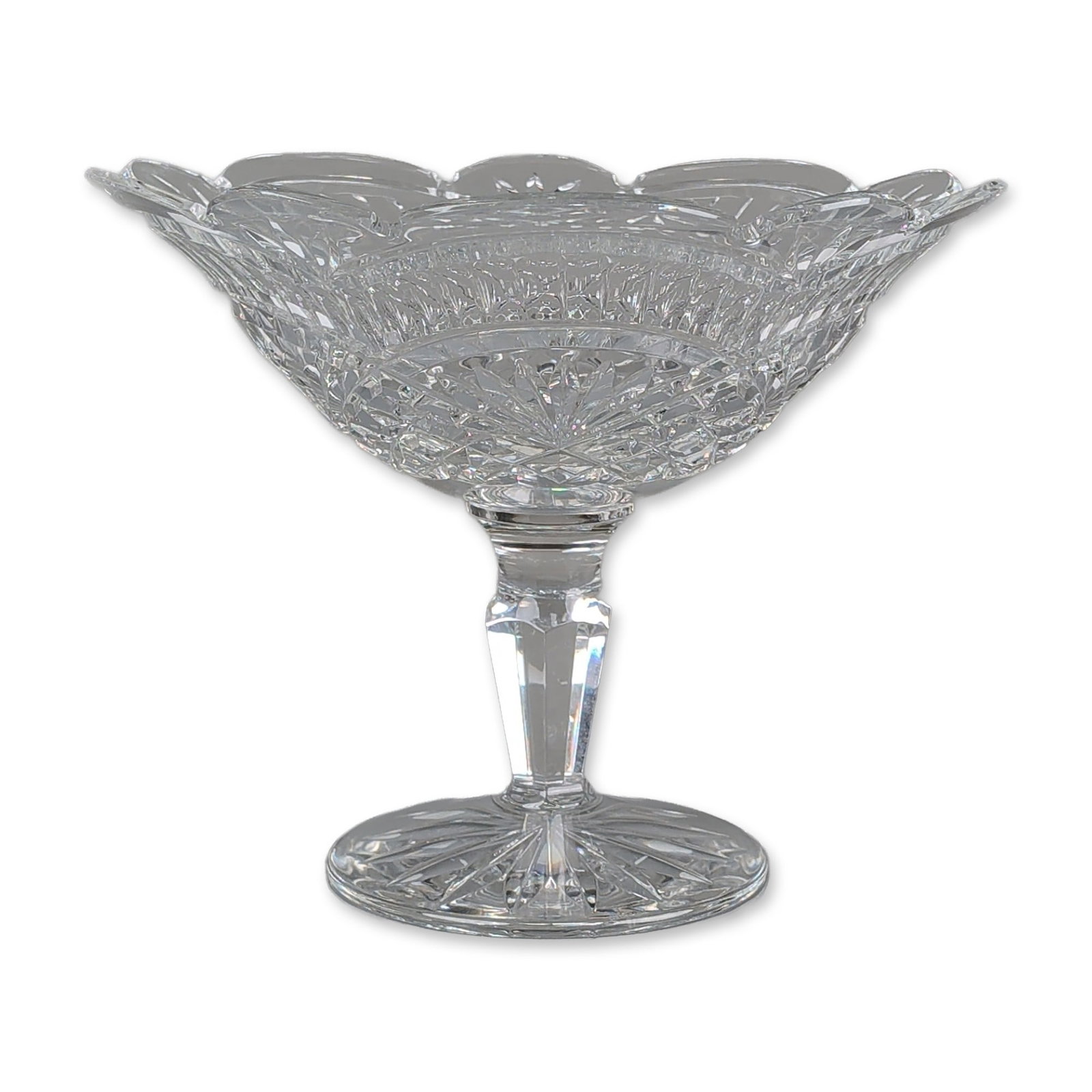 Waterford Crystal Artisan Pedestal Compote Bowl: Waterford lead crystal footed compote bowl featuring a flared body with a multi-lobed scalloped rim. The decorative program consists of deep vertical mitre cuts, fan motifs, and a central band of diam