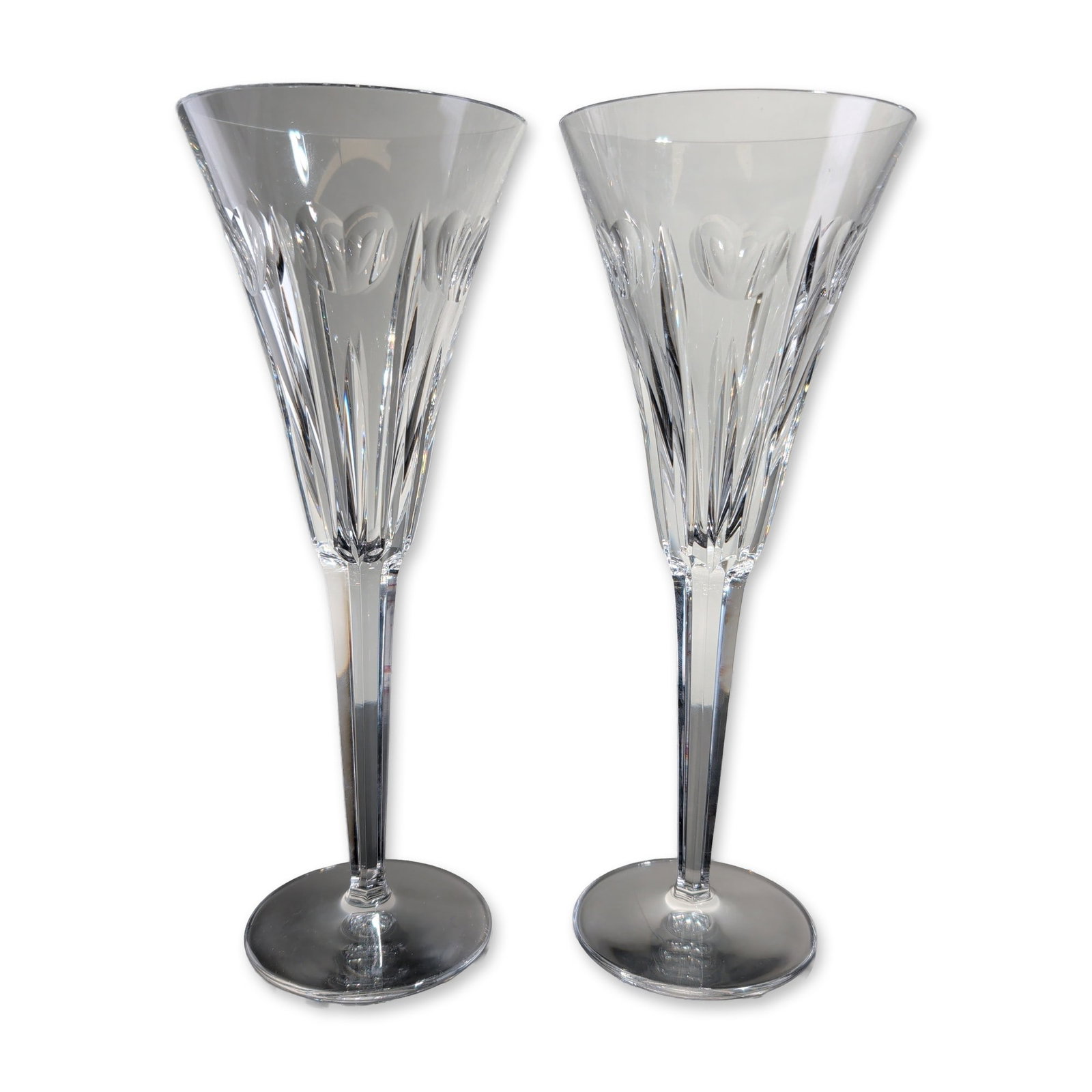 2pc Waterford Millennium Collection Love Crystal Champagne Flutes: Waterford pair of champagne flutes in lead crystal from the Millennium Collection in the Love pattern, featuring flared conical bowls decorated with vertical wedge and flute cuts and polished oval acc