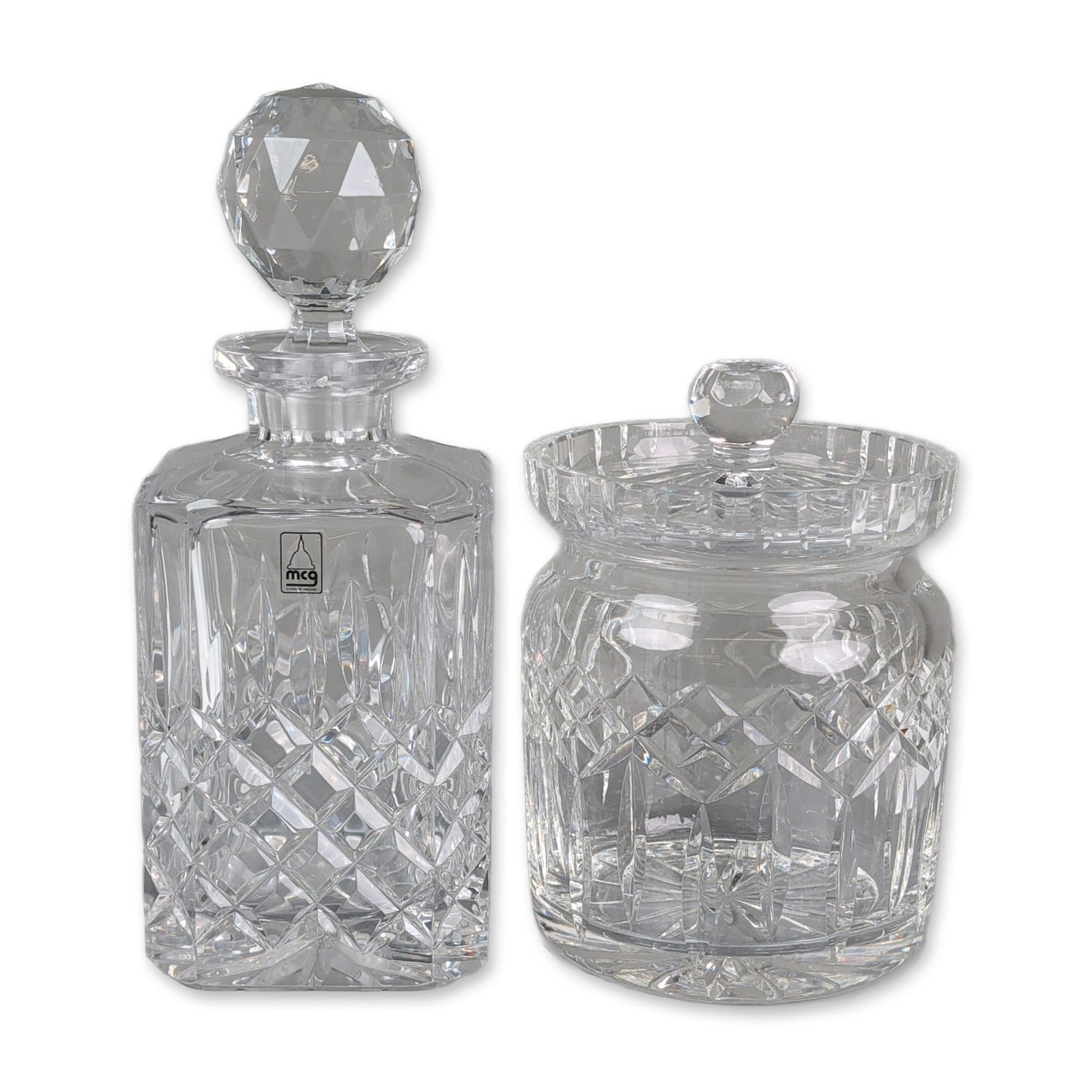 2pc Metropolitan Crystal Glassworks and Waterford Decanter and Lismore Biscuit Barrel: This grouping comprises a square spirit decanter and a Waterford Lismore biscuit barrel, both decorated with a combination of deep diamond-cut cross-hatching and vertical wedge cuts. The decanter feat