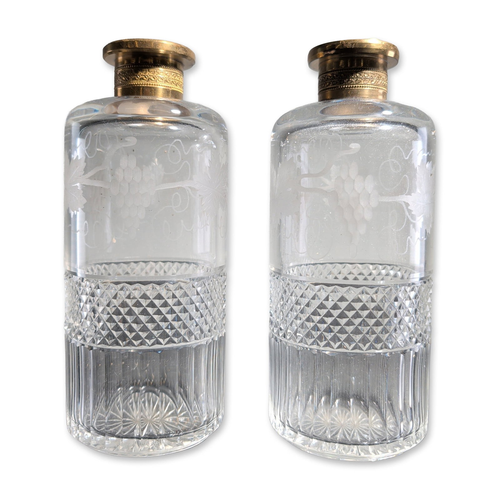 2pc Antique French Style Cut Crystal Decanters: Pair of late 19th-century European cylindrical decanters in cut and etched crystal. The decorative scheme features a wheel-etched frosted grapevine and leaf motif at the shoulder, a central band of