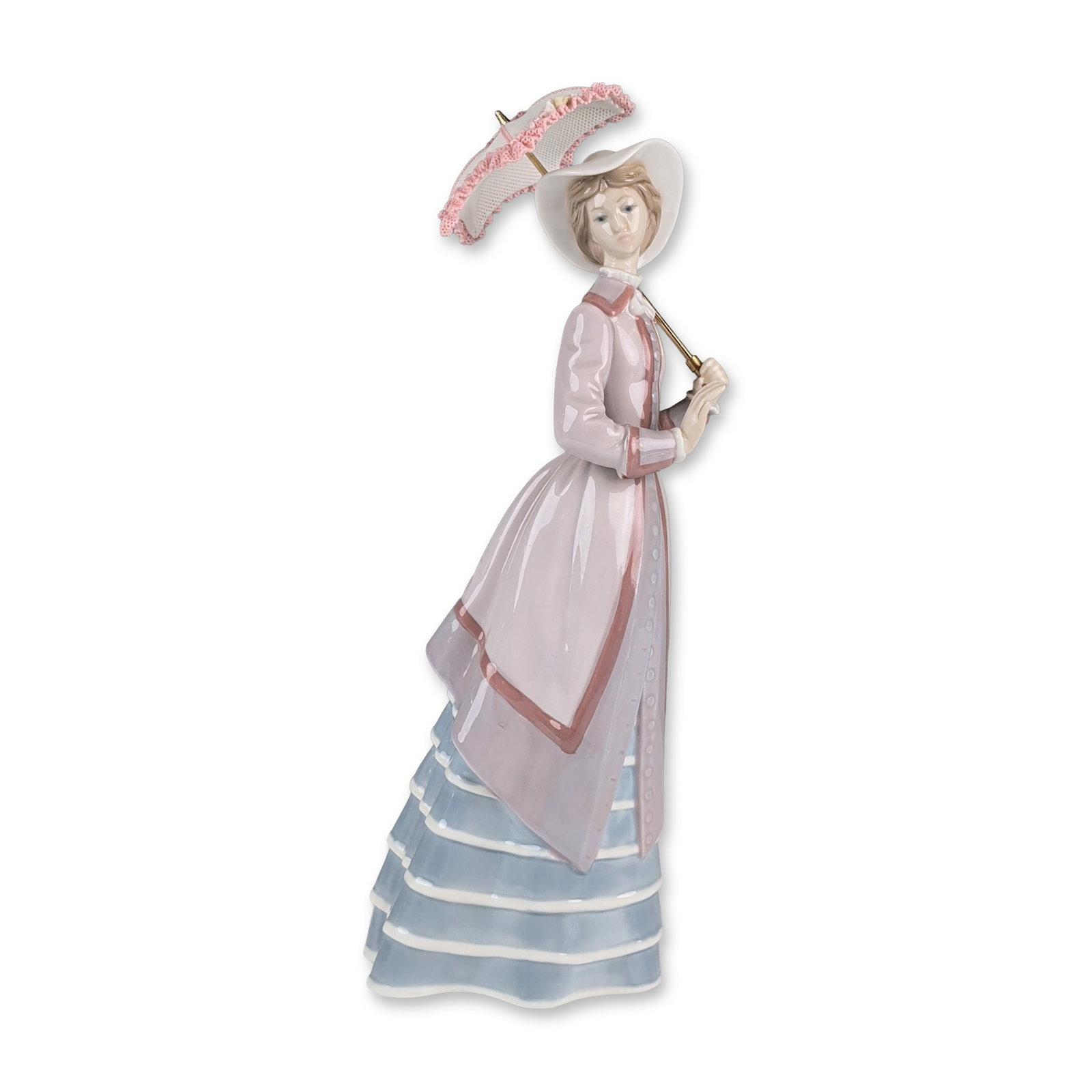 Lladro Porcelain Figurine, Parisian Lady 01005321: Lladro. Glazed porcelain figurine issued in 1985 and designed by Jose Puche. The figure is modeled in a walking pose wearing a wide-brimmed white hat and a lavender-toned coat with rose-colored trim o