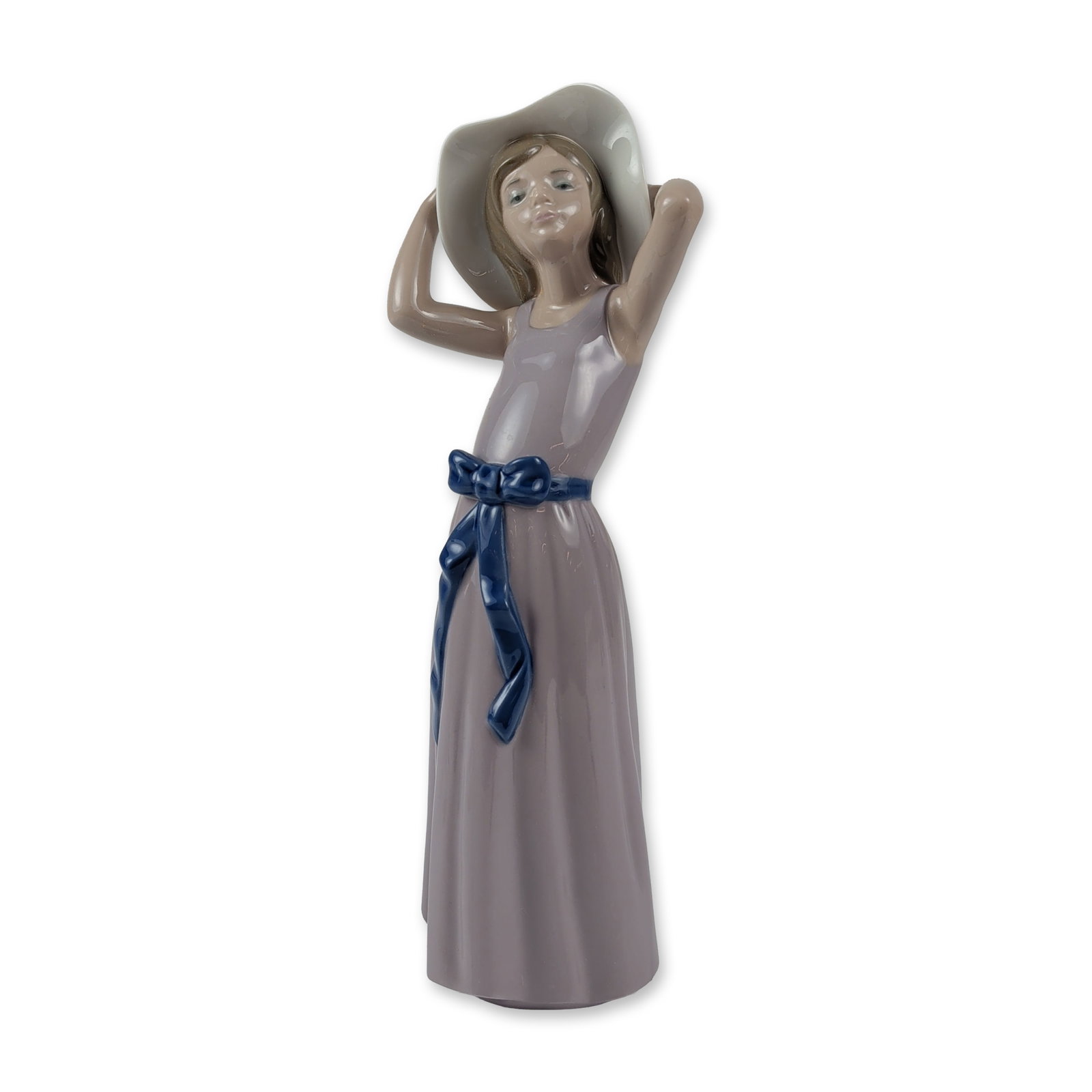 Lladro Glazed Porcelain Figurine, Coy 01005011: Spanish Lladro glazed porcelain figurine, model number 1005011, titled Coy. The piece depicts a young girl in a lavender gown with a dark blue waist sash, holding a cream-colored sun hat with a light 