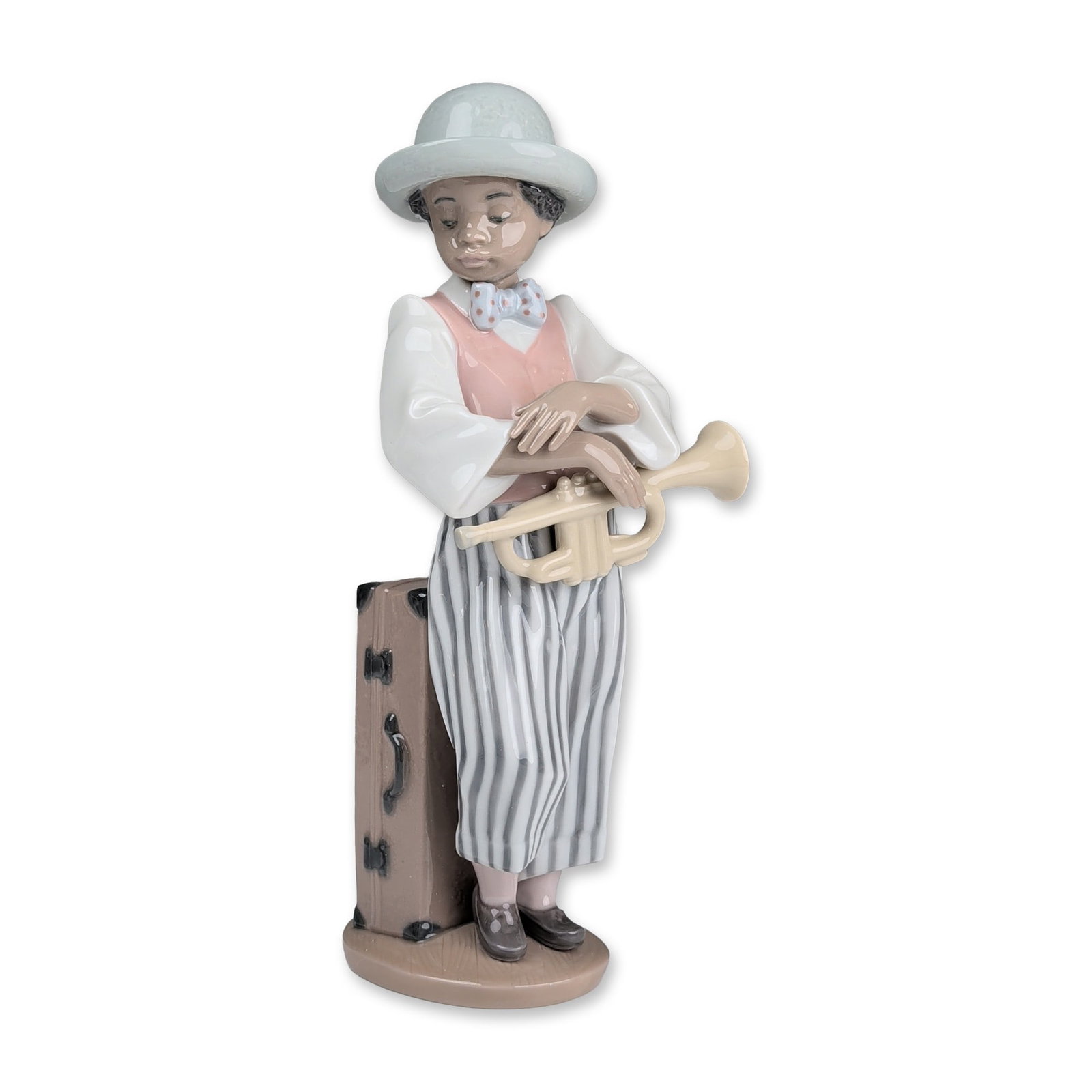 Lladro Porcelain Figurine, Jazz Horn 01005832: Jazz glazed porcelain figurine designed by Rafael Lozano and issued in 1991. The hand-painted figure depicts a young boy wearing a light blue hat, white long-sleeved shirt, pink vest, and grey and whi