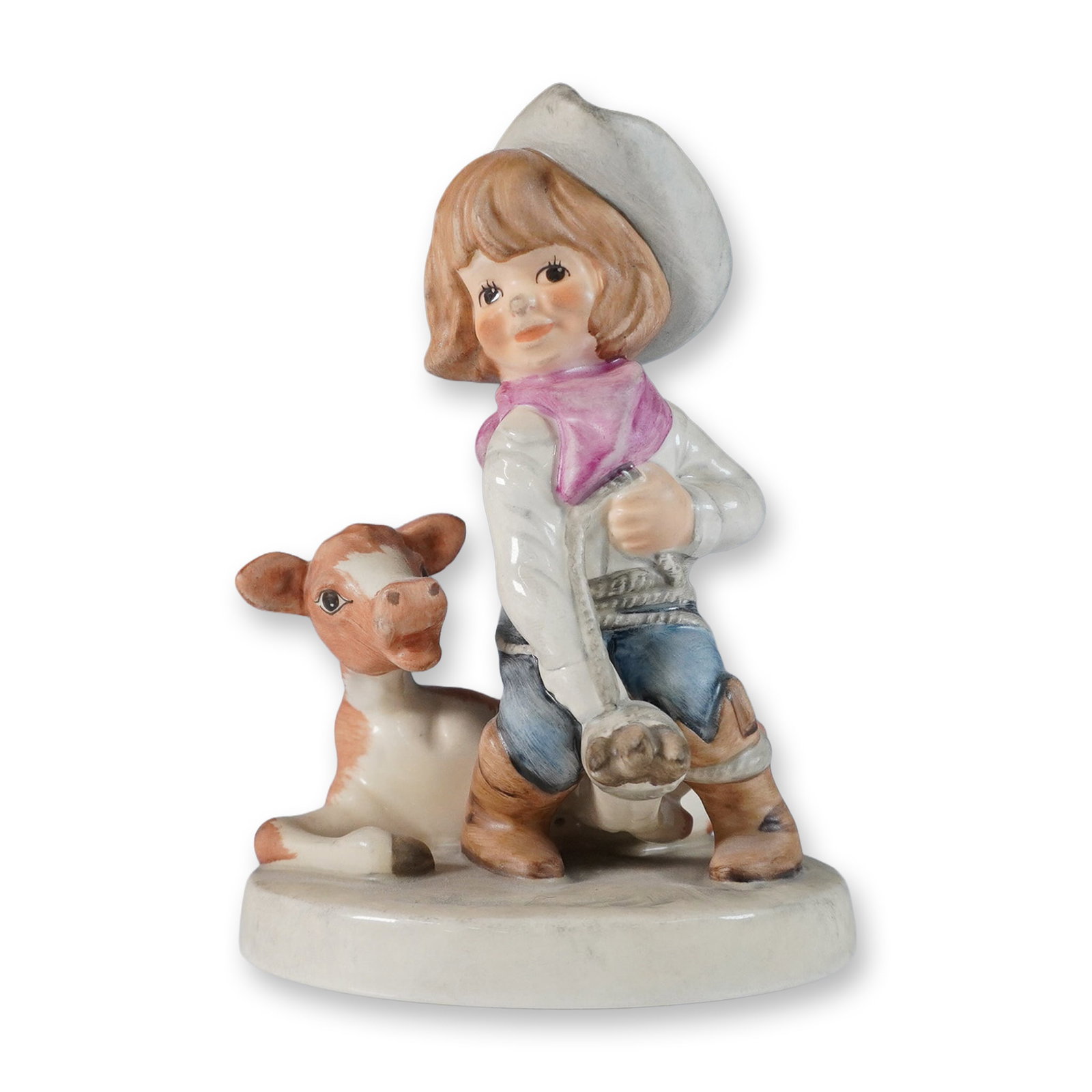 Goebel Figurine, Cowgirl Rodeo: This Goebel figurine, titled Cowgirl Rodeo, captures a charming Western-themed scene of a young cowgirl kneeling beside a cow, dressed in a white cowboy hat, pink bandana, and denim jeans. The figurin