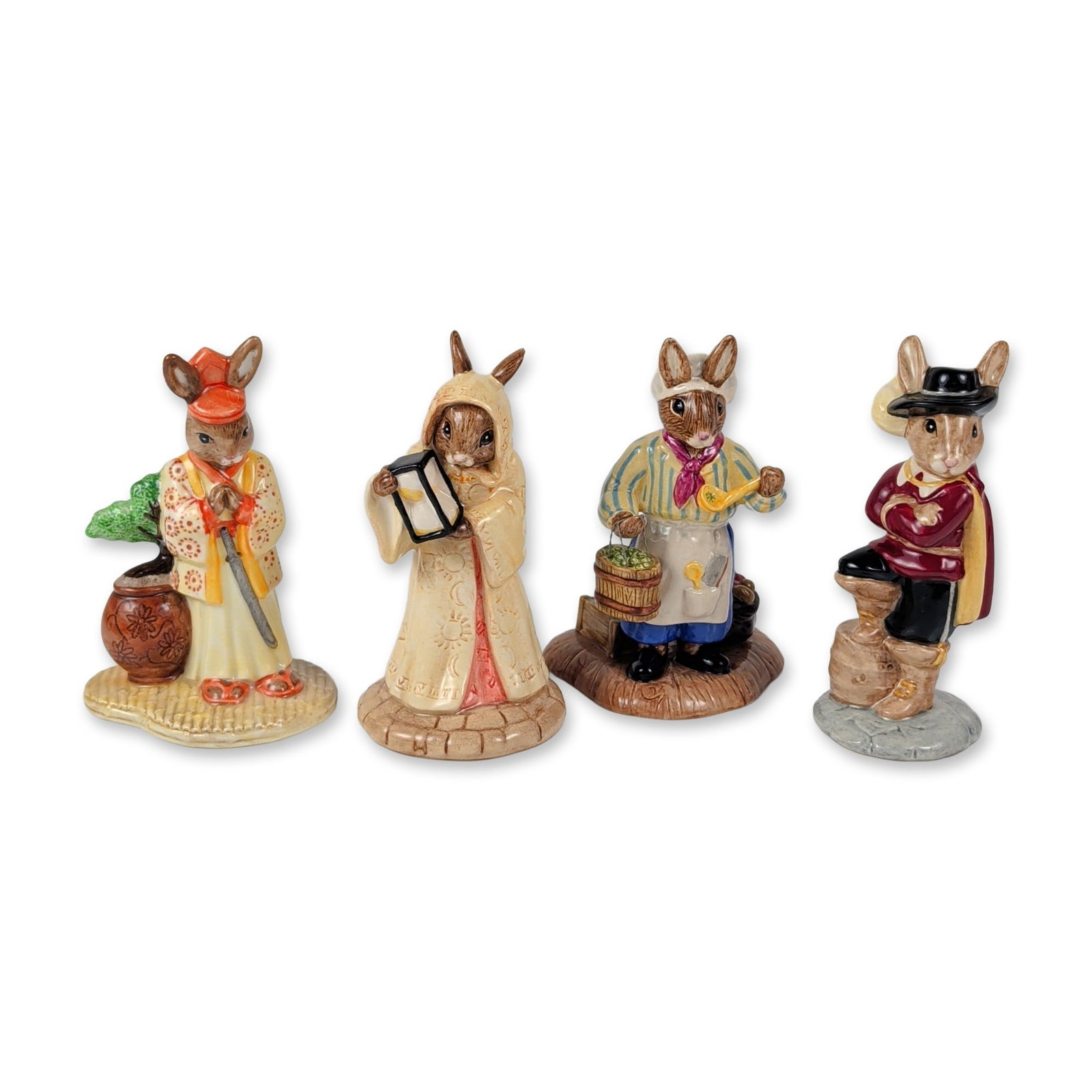 4pc Royal Doulton Bunnykins Costumed Character Figures Collection: This four-piece collection of hand-painted glazed ceramic figurines from the Royal Doulton Bunnykins line features anthropomorphic rabbit characters in specialized thematic costumes. The grouping cons