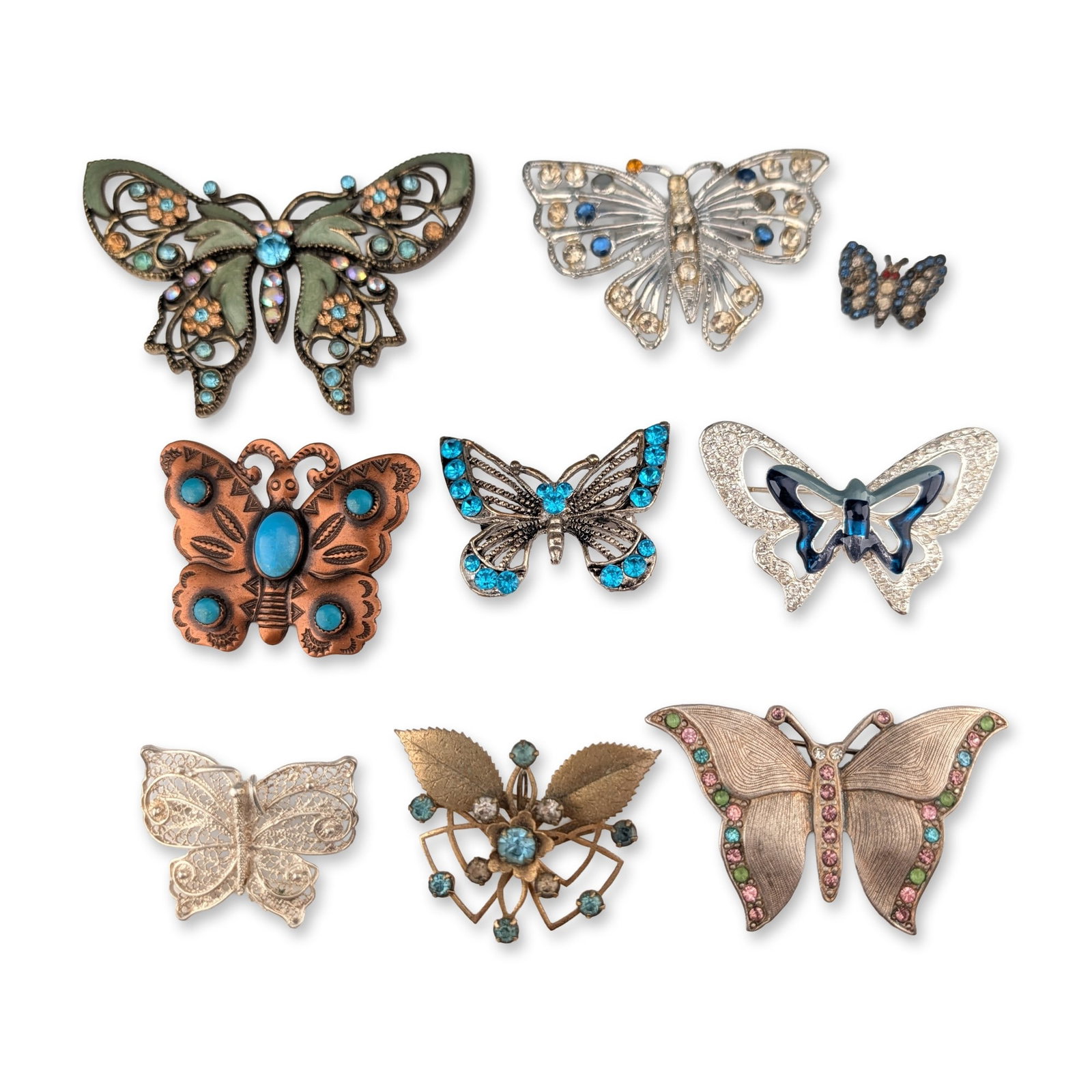 9pc Collection of Butterfly Motif Costume Jewelry Brooches: A collection of nine costume jewelry brooches in various metal finishes featuring butterfly motifs. The group includes an ornate antique gold-tone butterfly with pierced wings set with green enamel an