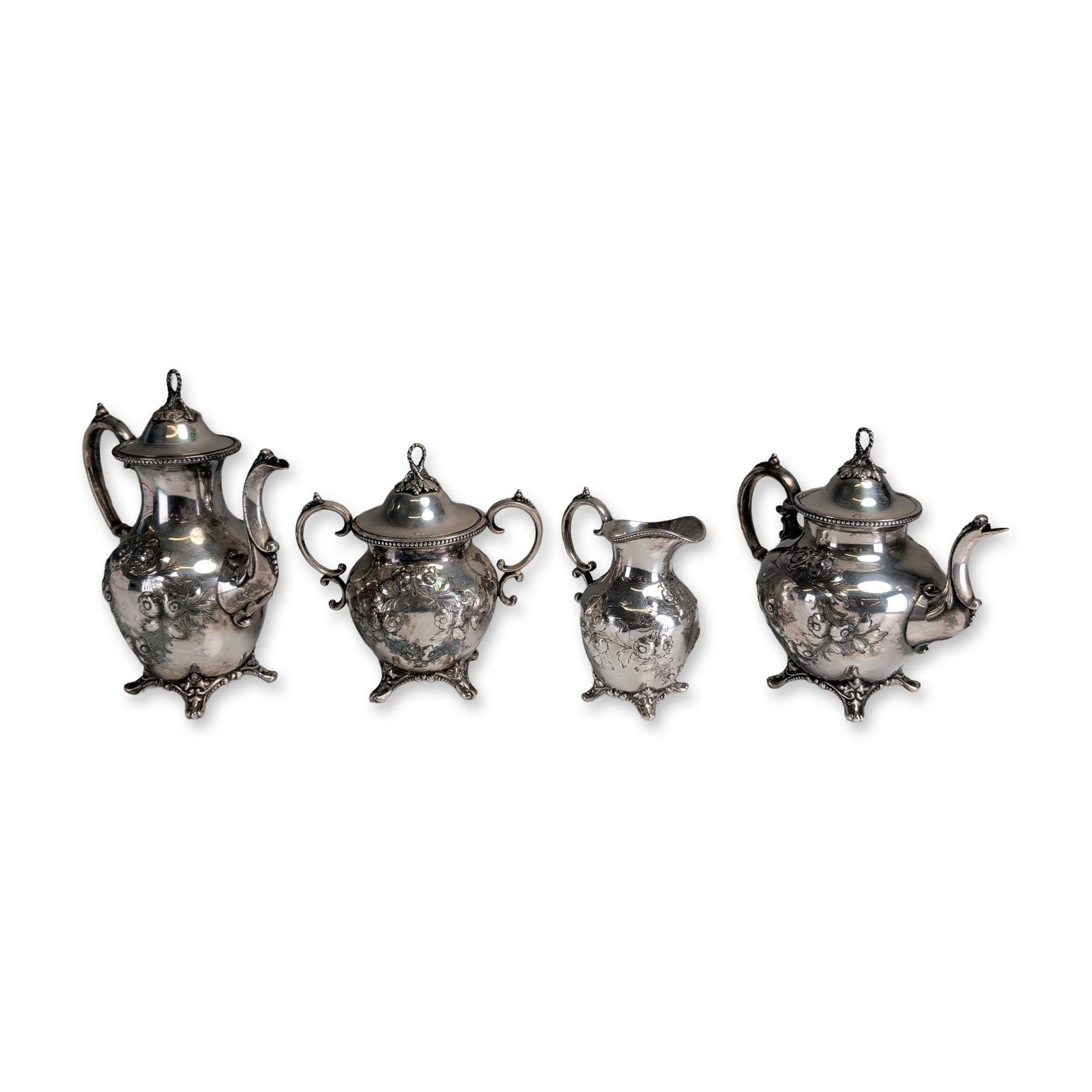 4pc Victorian Style Silver-Toned Tea and Coffee Service: Victorian Rococo Revival style silver-toned tea and coffee service featuring heavy repousse and chased decoration of floral bouquets, shells, and scrolling foliage against a textured ground. The set i
