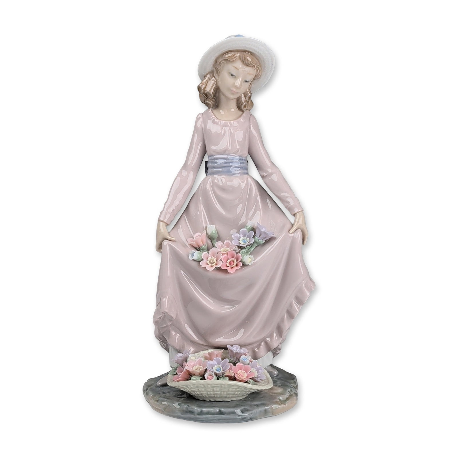 Lladro Porcelain Figurine, Flower Curtsey 01005027: Lladro, Spain. Glazed porcelain figurine designed by Vincente Martinez. The figure depicts a young woman in a flowing pink dress with a ruffled hem and light blue sash, wearing a wide-brimmed sun hat.