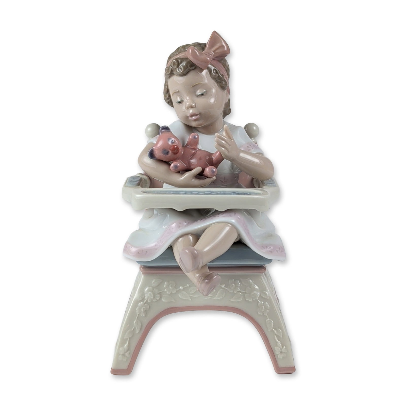 Lladro Porcelain Figurine, Little Bear 1006299: Porcelain figurine, model 1006299, designed by sculptor Joan Coderch. The glazed porcelain work depicts a child seated in a floral-decorated highchair cradling a pink teddy bear, finished in a high-gl