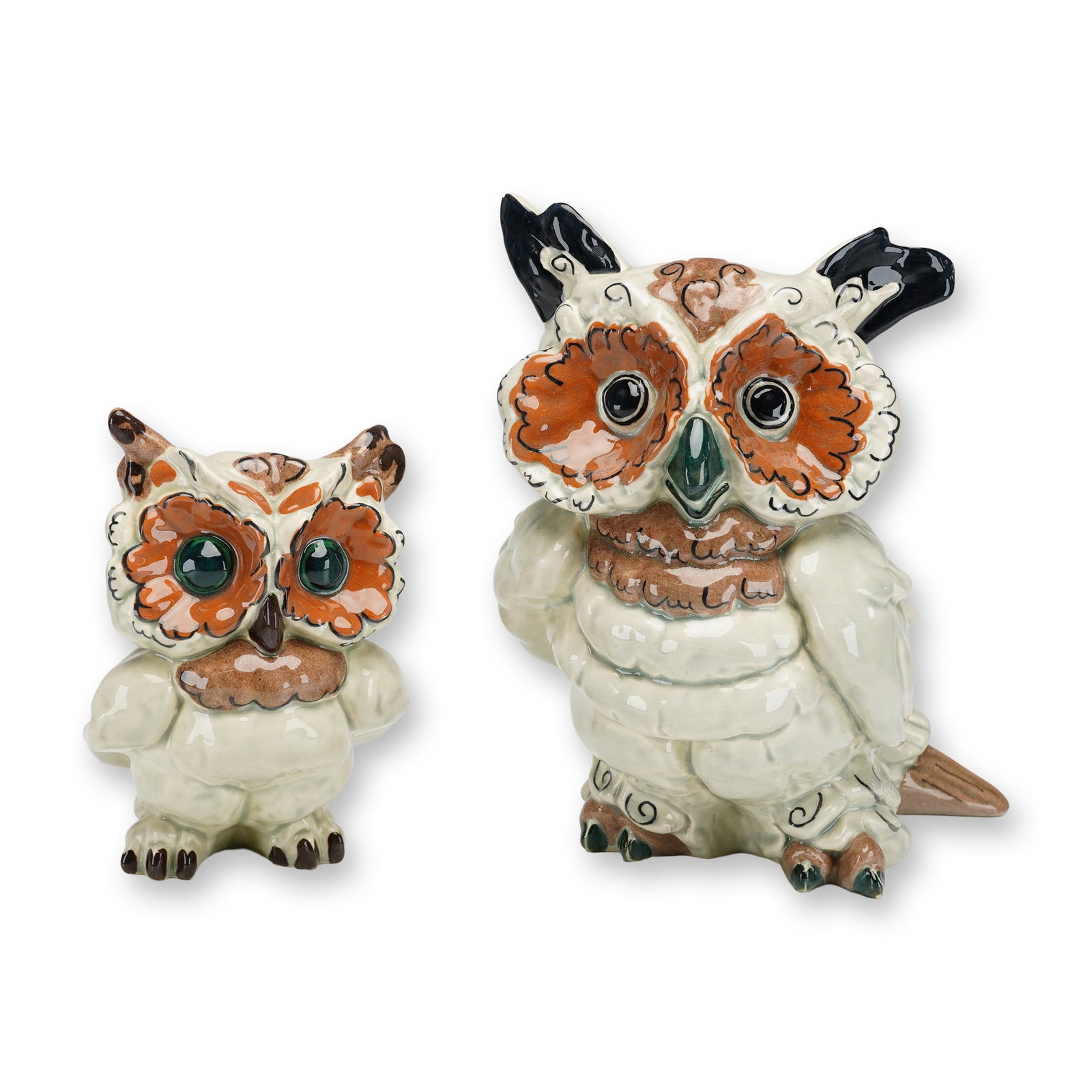 Two Kay Finch California Pottery Figurines, Hoot and Toot: These slip-cast figures feature a creamy off-white glaze with hand-painted accents in shades of brown, orange, black, and green. The design incorporates stylized scrollwork and textured plumage charac