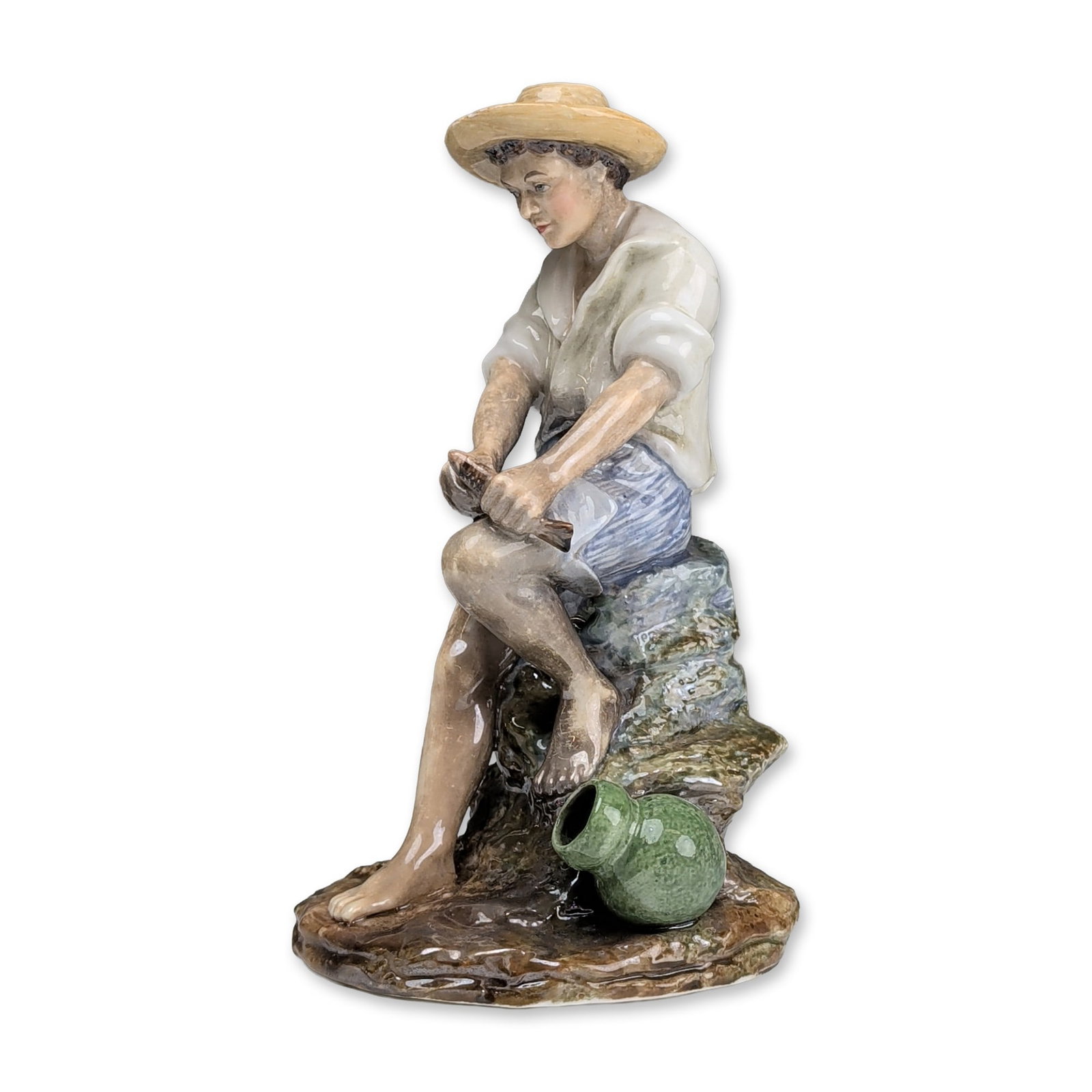 Reginald "Reg" Johnson Studio Pottery Figurine, The Fisher Boy: Polychrome glazed ceramic figure depicting a young boy in 19th-century attire after the sculpture by Vincenzo Gemito. Form features a yellow straw hat, white shirt, and blue striped shorts, modeled in