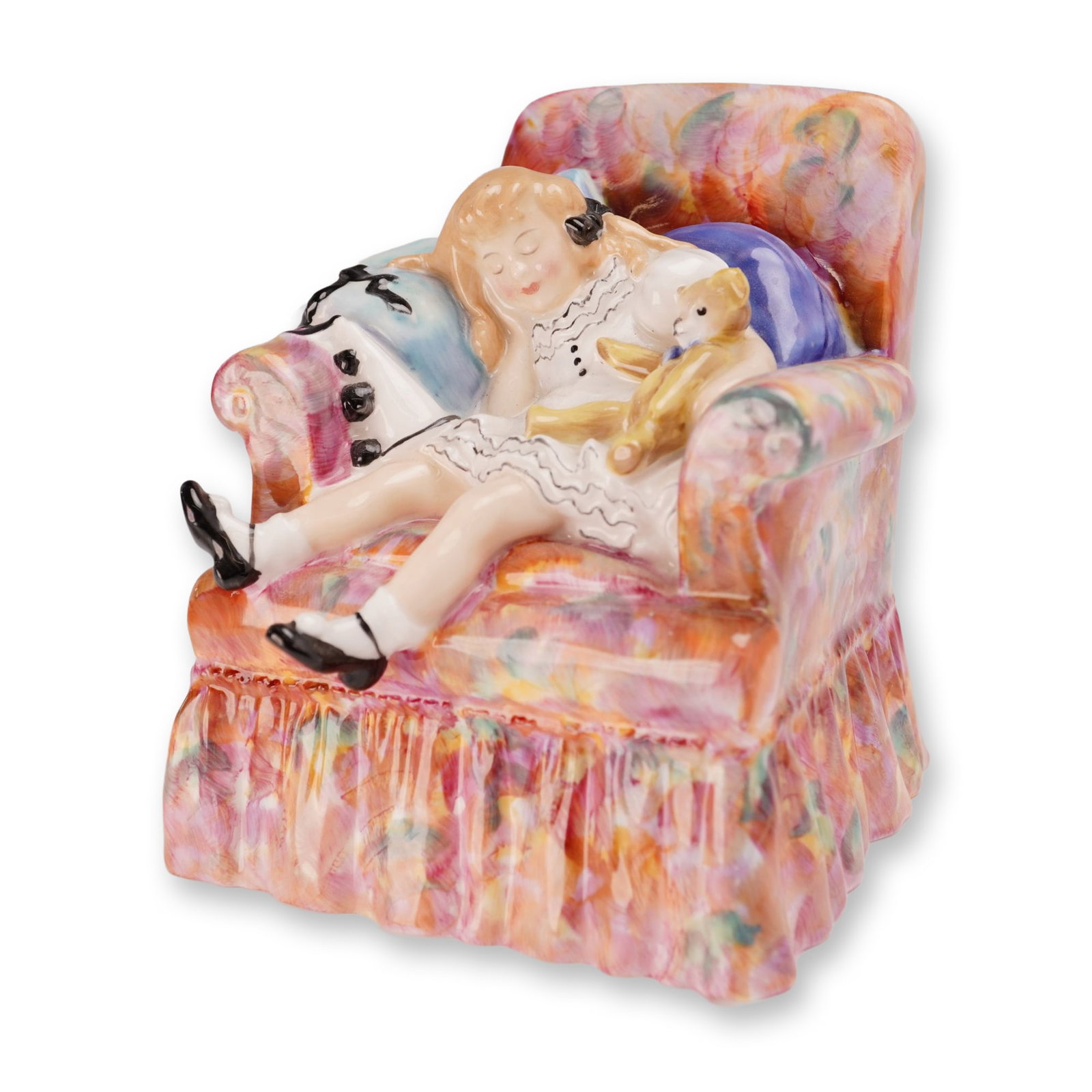 Royal Doulton Bone China Figurine, Sleepyhead HN2114: Designed by Peggy Davies. The figure depicts a young blonde girl sleeping in an overstuffed armchair decorated with a multicolored floral pattern in shades of pink, orange, yellow, and green. She is c