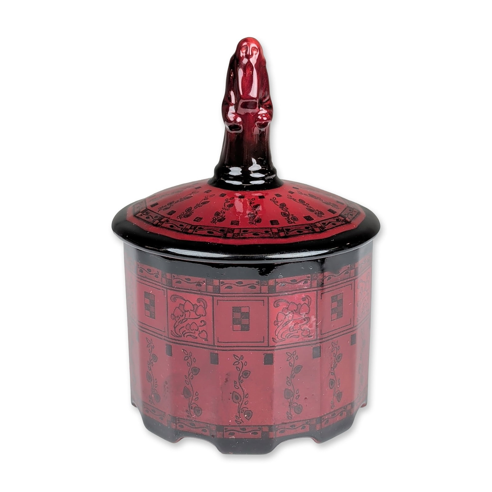Royal Doulton Flambe Art Deco Lidded Vanity Box, Wise Man: Octagonal ceramic lidded jar featuring a deep red flambe glaze and a figure of a standing bearded man finial. The faceted body and lid are decorated with black-printed panels depicting scrolling vines