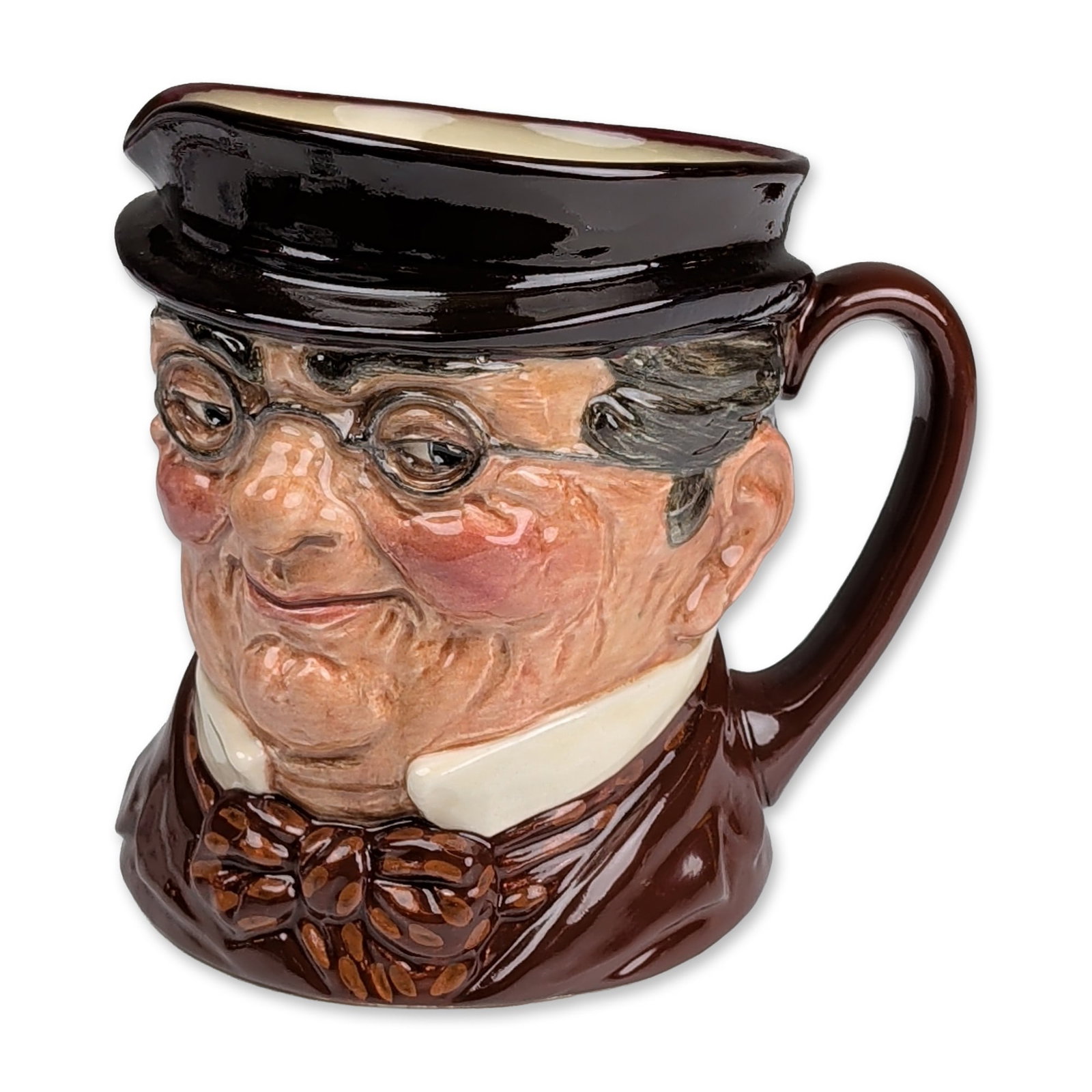 Royal Doulton Colorway Large Character Jug, Mr. Pickwick D6060: Depicting the Charles Dickens character Mr. Pickwick. The bust is modeled with spectacles, a black hat, and a brown coat with a patterned bow tie. The side of the jug features the embossed name Mr. Pi