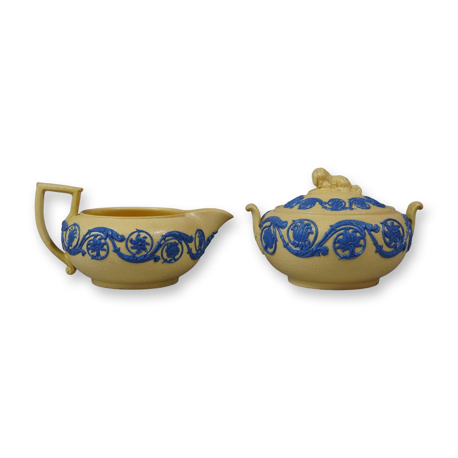 2pc Wedgwood Blue Relief Cane Stoneware Creamer and Covered Sugar Bowl: A matching pair of mid-19th-century Minton cane stoneware vessels comprising a creamer and a covered sugar bowl. Both pieces are crafted from a buff-colored stoneware body with a textured smeared glaz